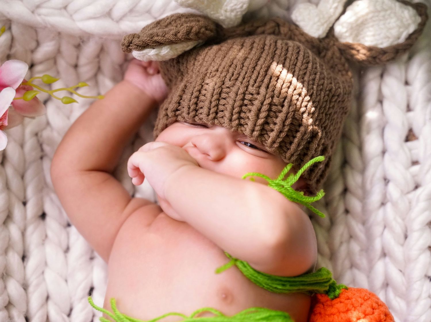 Baby's feet wrapped in cozy knit blanket with strawberry decoration.