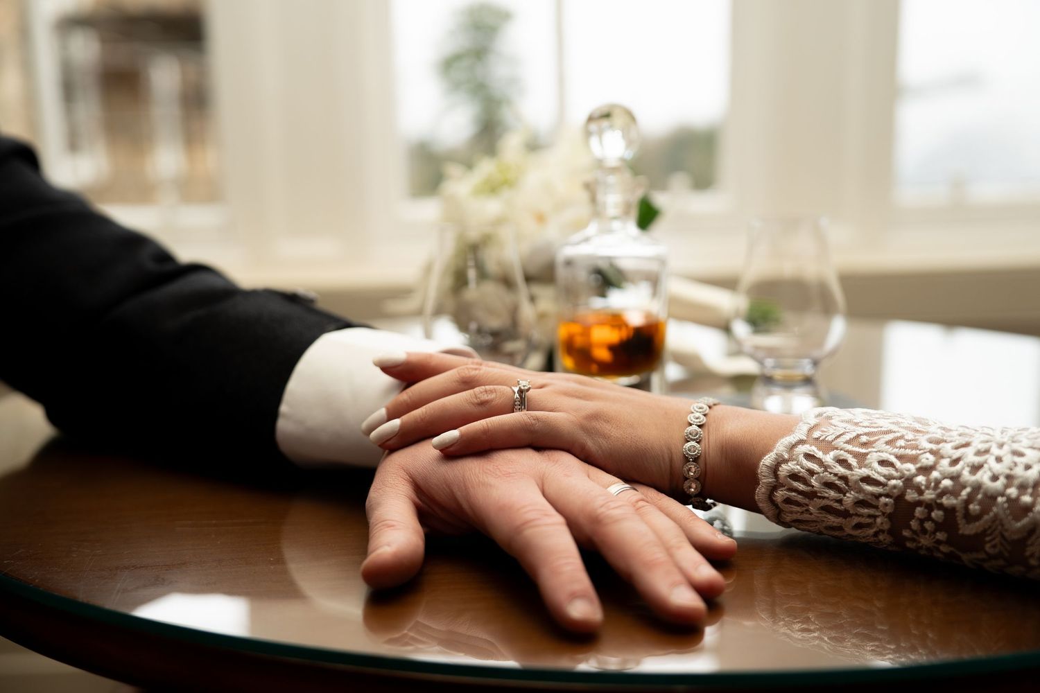 Hands resting on wooden table during intimate wedding moment.