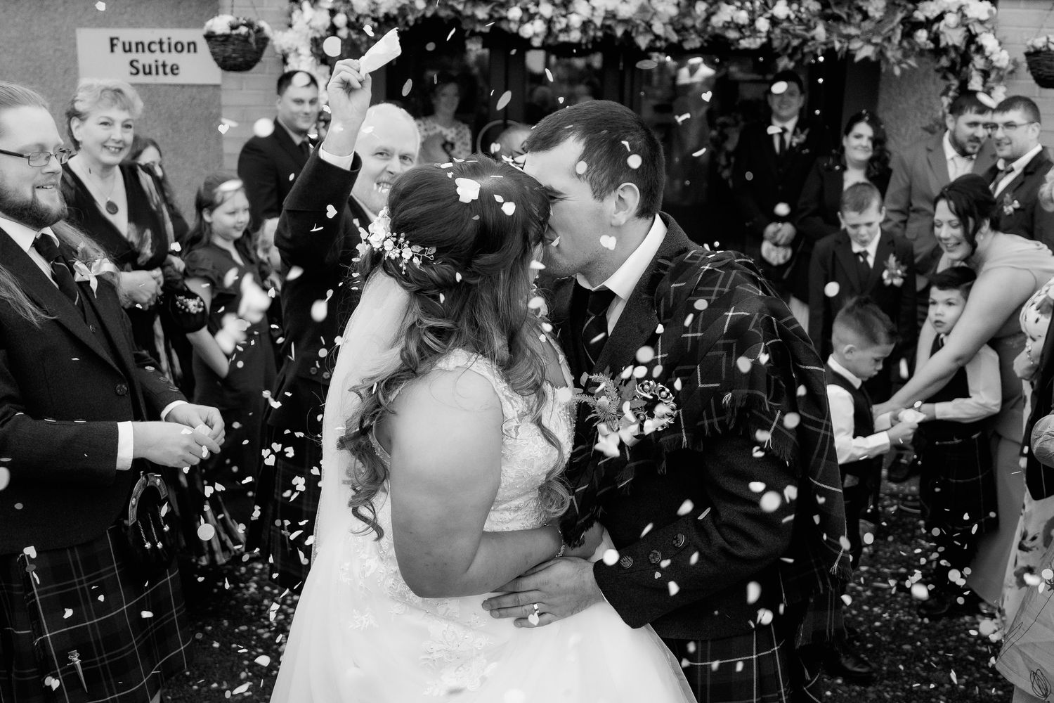 Wedding party celebrating with confetti showering down in black and white photography.
