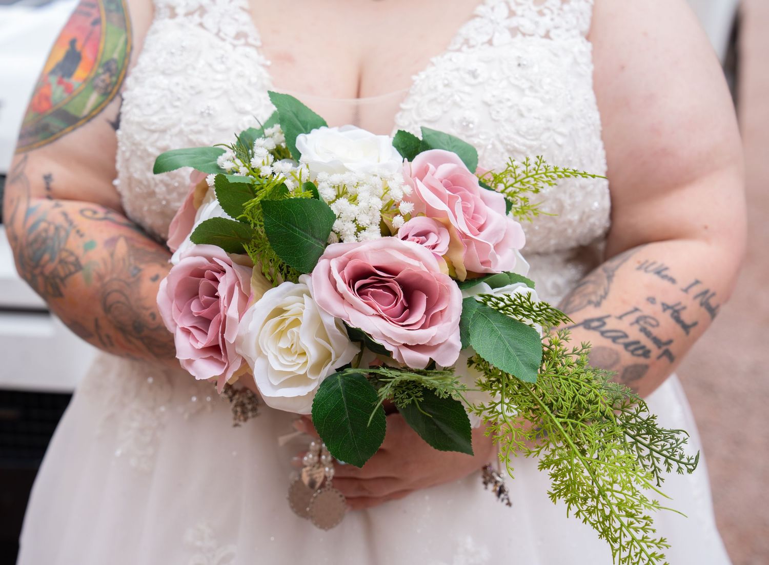 Close-up shots of pink and white rose bouquets being held at a wedding ceremony with floral arrangements.