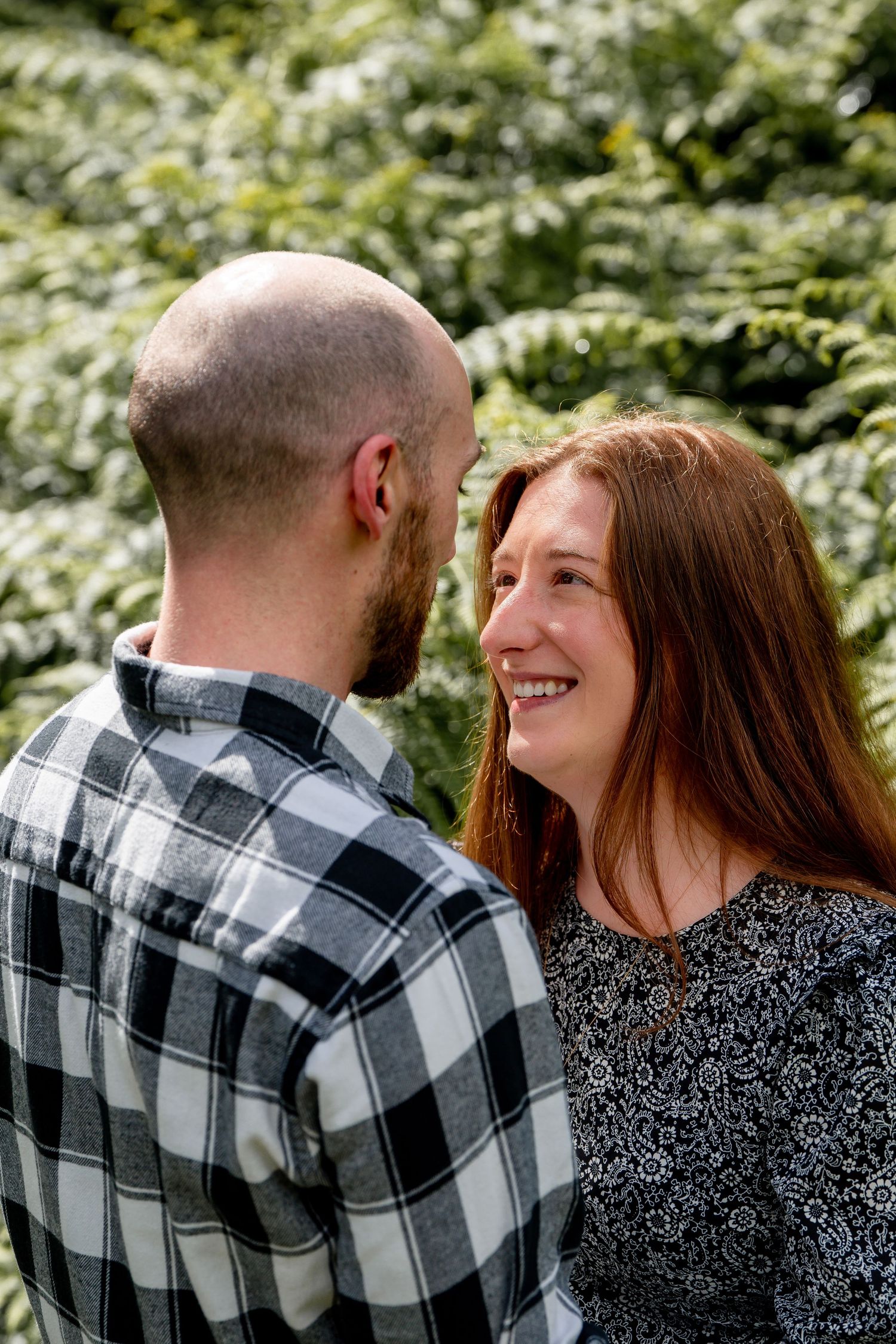 Romantic couple in a natural setting wearing plaid and sparkly sweaters share tender moments in a photo series.