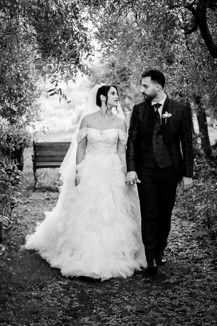 sposi che passeggiano tra l’oliveta di perlamora matrimonio in toscana