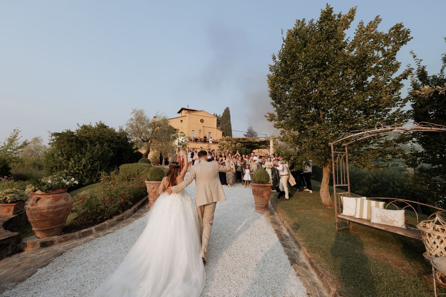 Gli sposi camminano lungo il viale verso Villa il Petriccio nella luce del tardo pomeriggio, Montespertoli