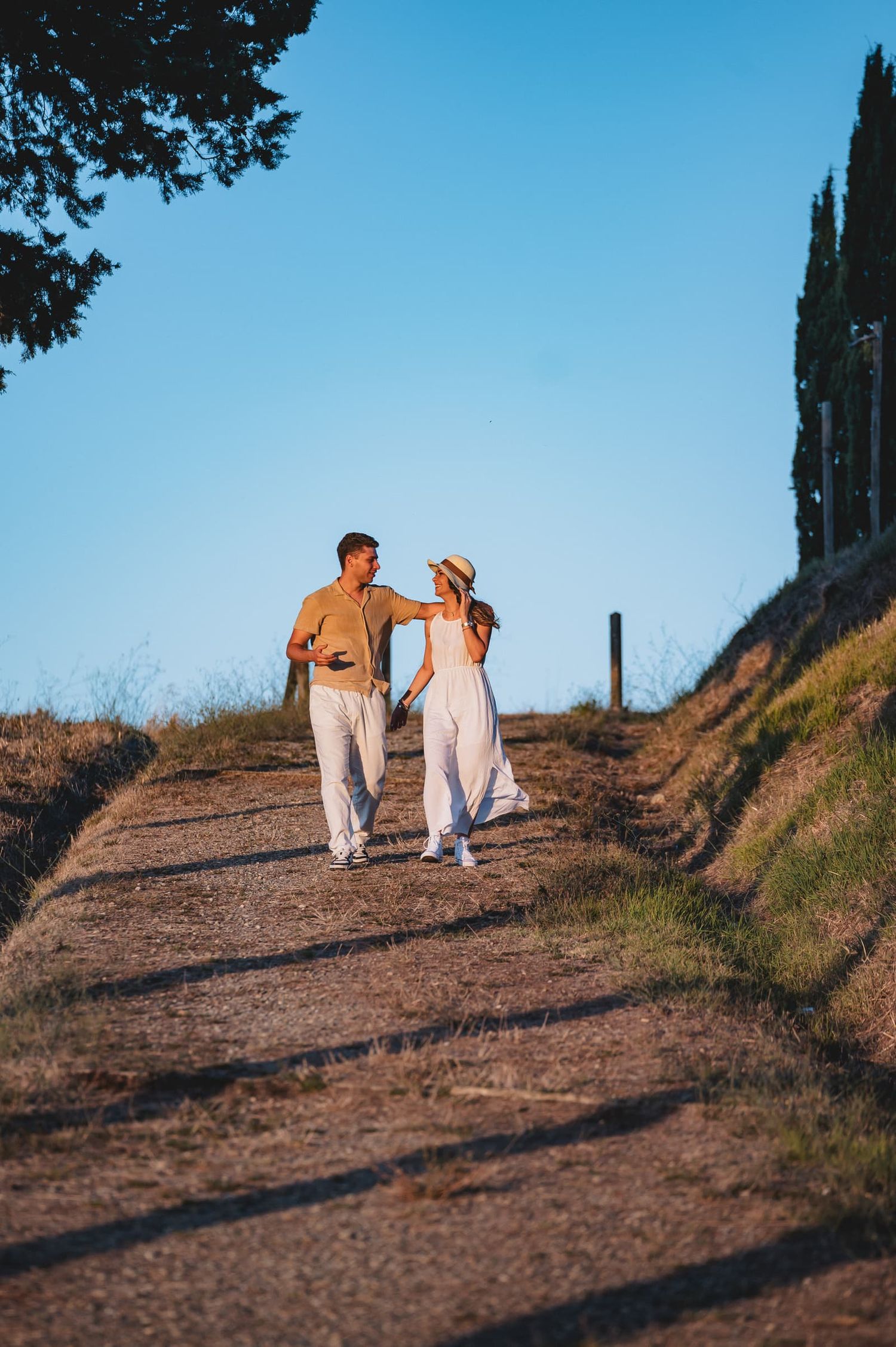 Elisa e Daniele camminano lungo un viale sterrato tra i cipressi, prematrimoniale al Parco di Canonica, Certaldo