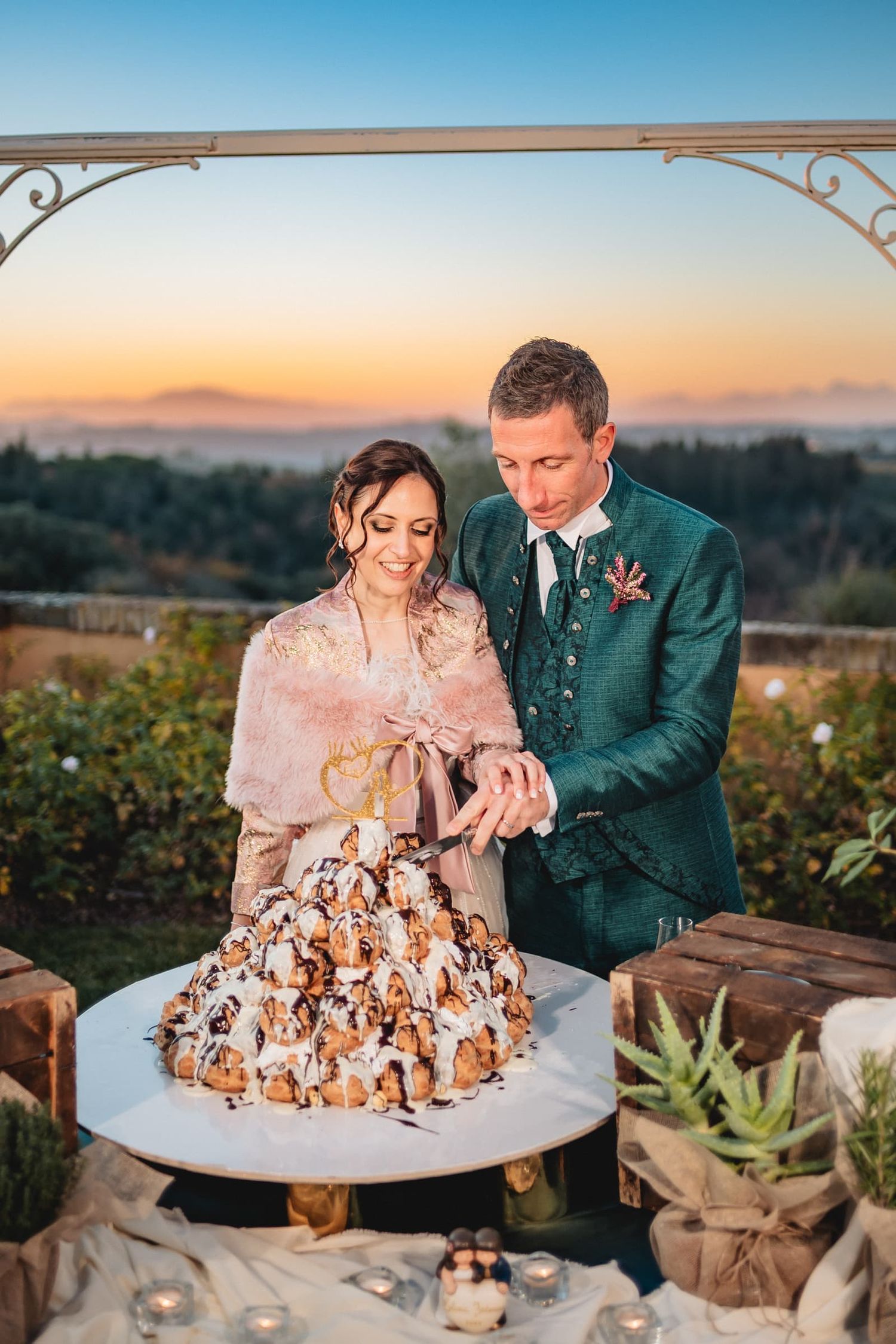 Elena e Federico tagliano la torta all'aperto al tramonto, matrimonio invernale a Villa il Petriccio, Montespertoli