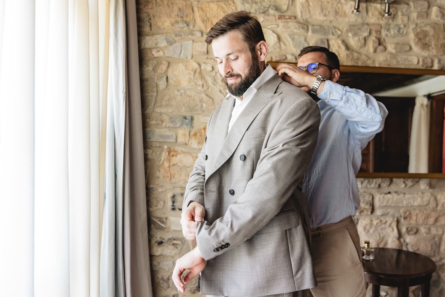 The groom adjusting his jacket by the stone wall, Villa Le Bolli, Radicondoli