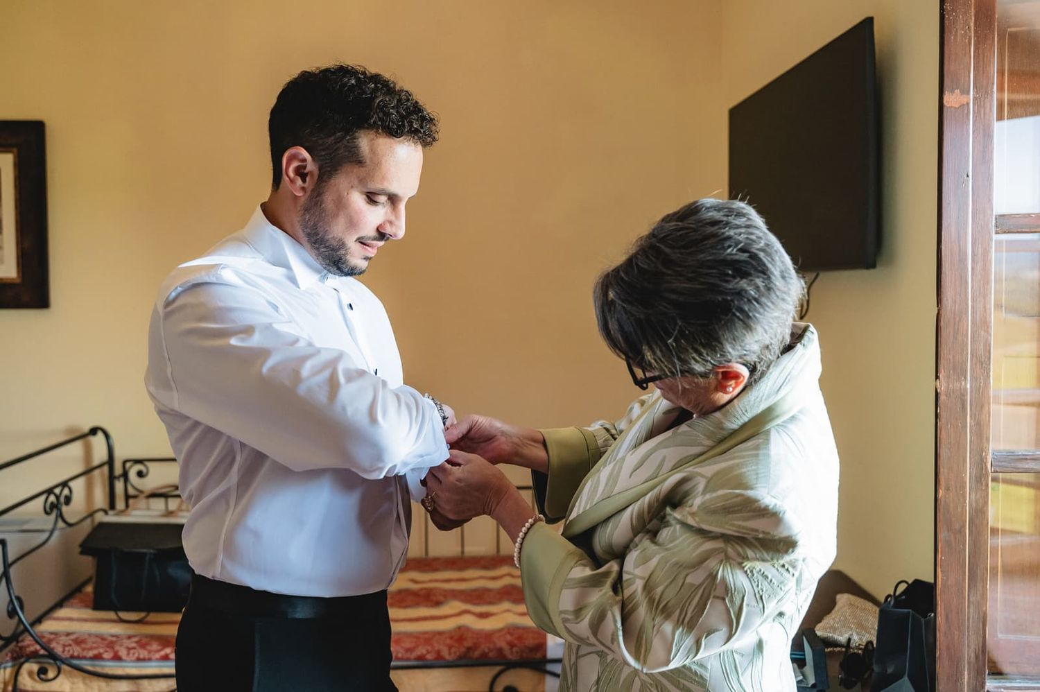 Preparativi dello sposo: una familiare gli sistema i polsini della camicia, matrimonio a Certaldo