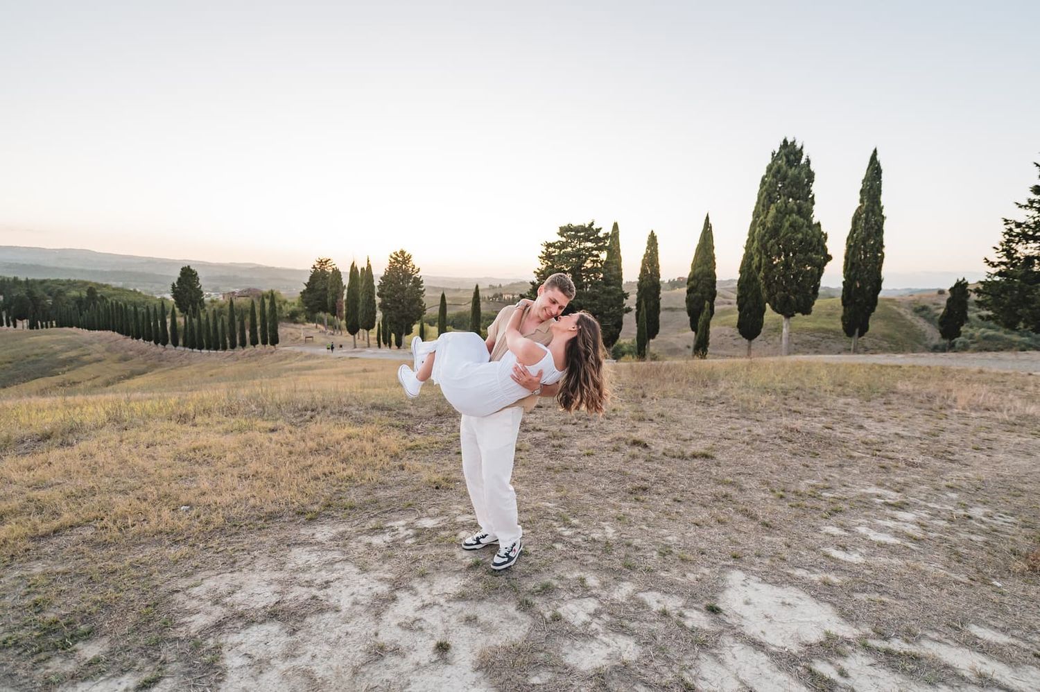 Daniele solleva Elisa sulle colline al tramonto, prematrimoniale in Toscana al Parco di Canonica, Certaldo