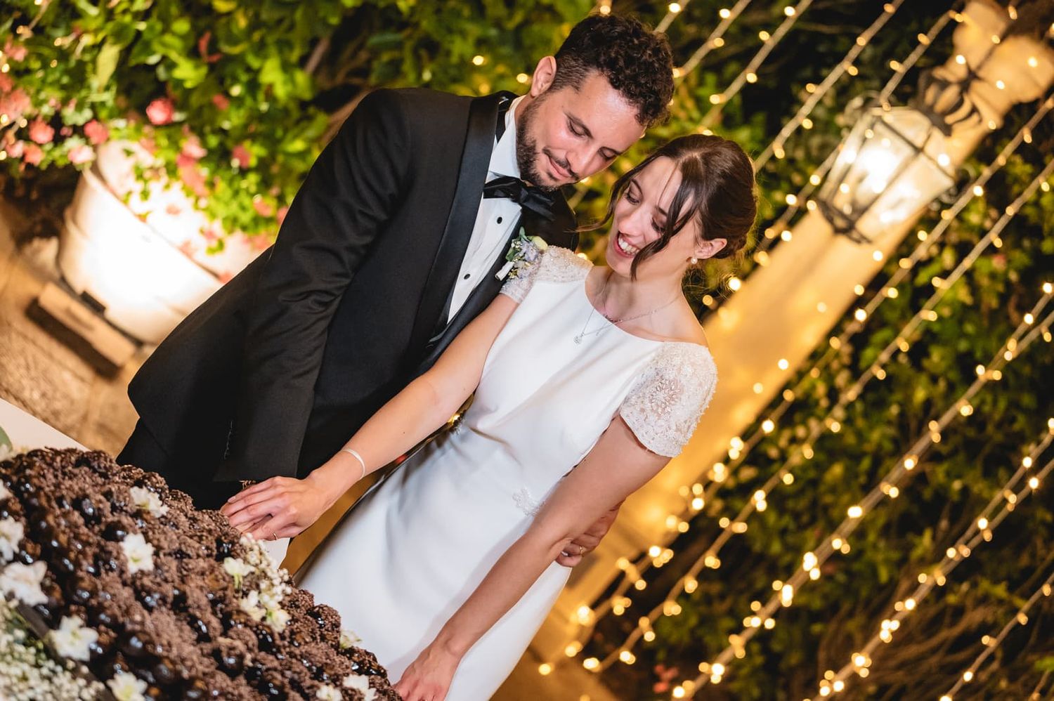 Martina e Gianluca tagliano la torta sotto le lucine, matrimonio all'Antica Fattoria Paterno, Montespertoli