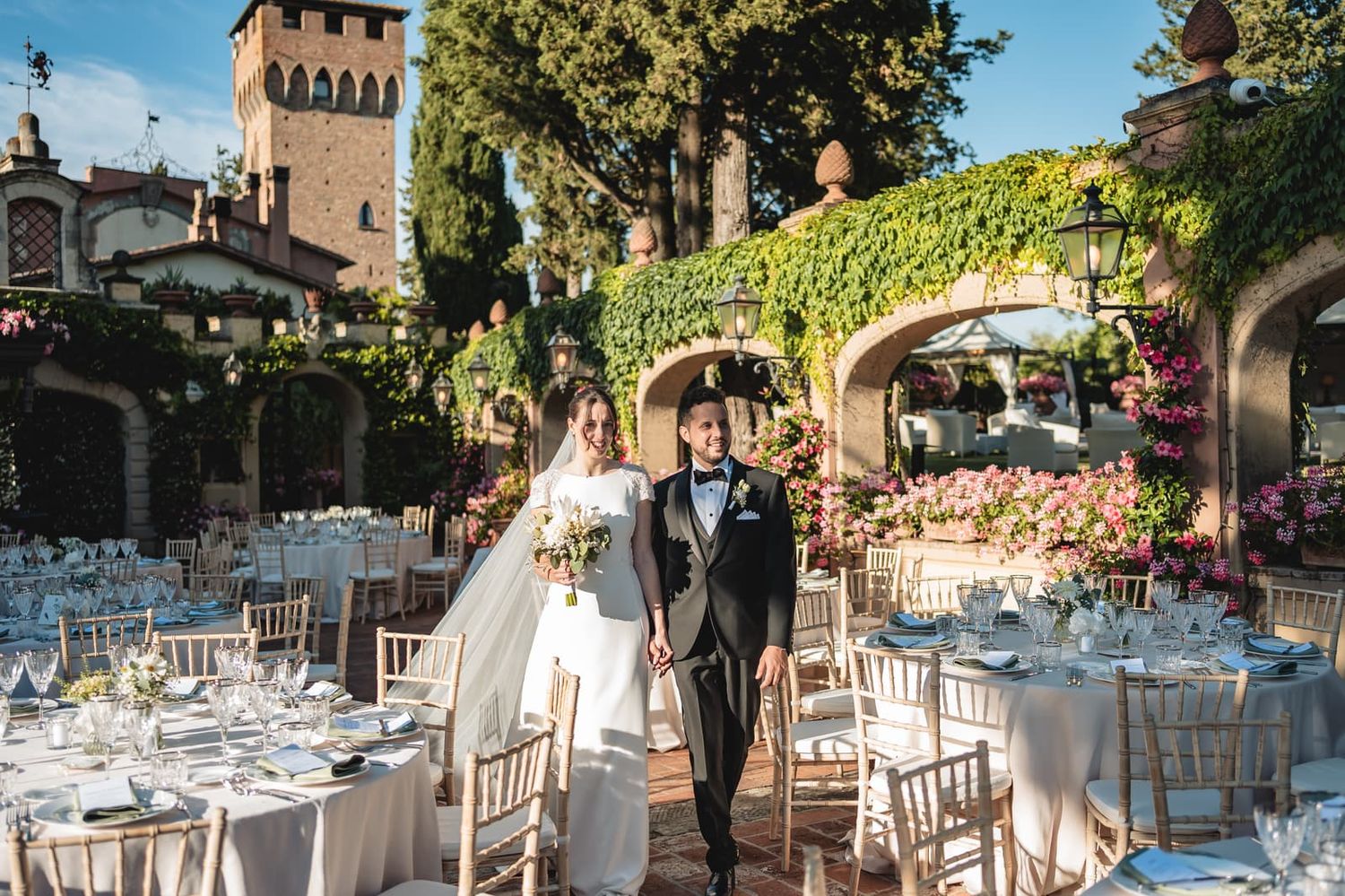 Gli sposi arrivano al ricevimento tra i tavoli sotto il pergolato fiorito dell'Antica Fattoria Paterno
