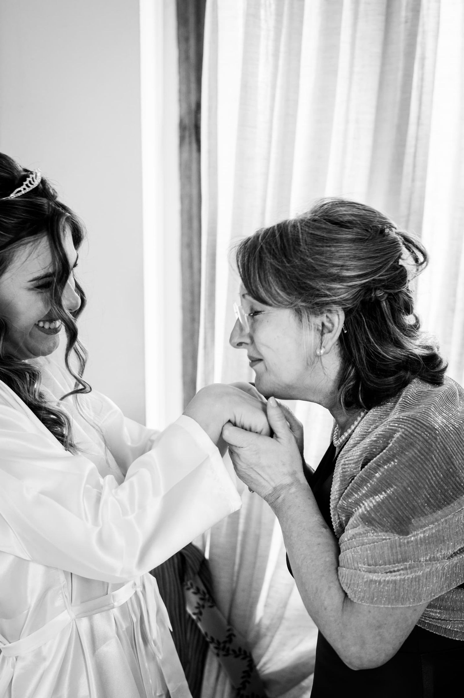 La sposa emozionata stringe la mano di una familiare durante i preparativi, bianco e nero