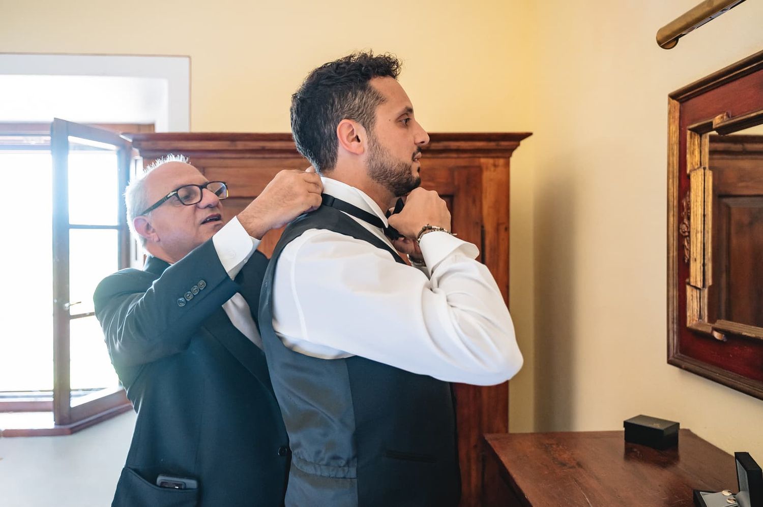 Lo sposo indossa il gilet aiutato da un familiare durante i preparativi, matrimonio a Certaldo