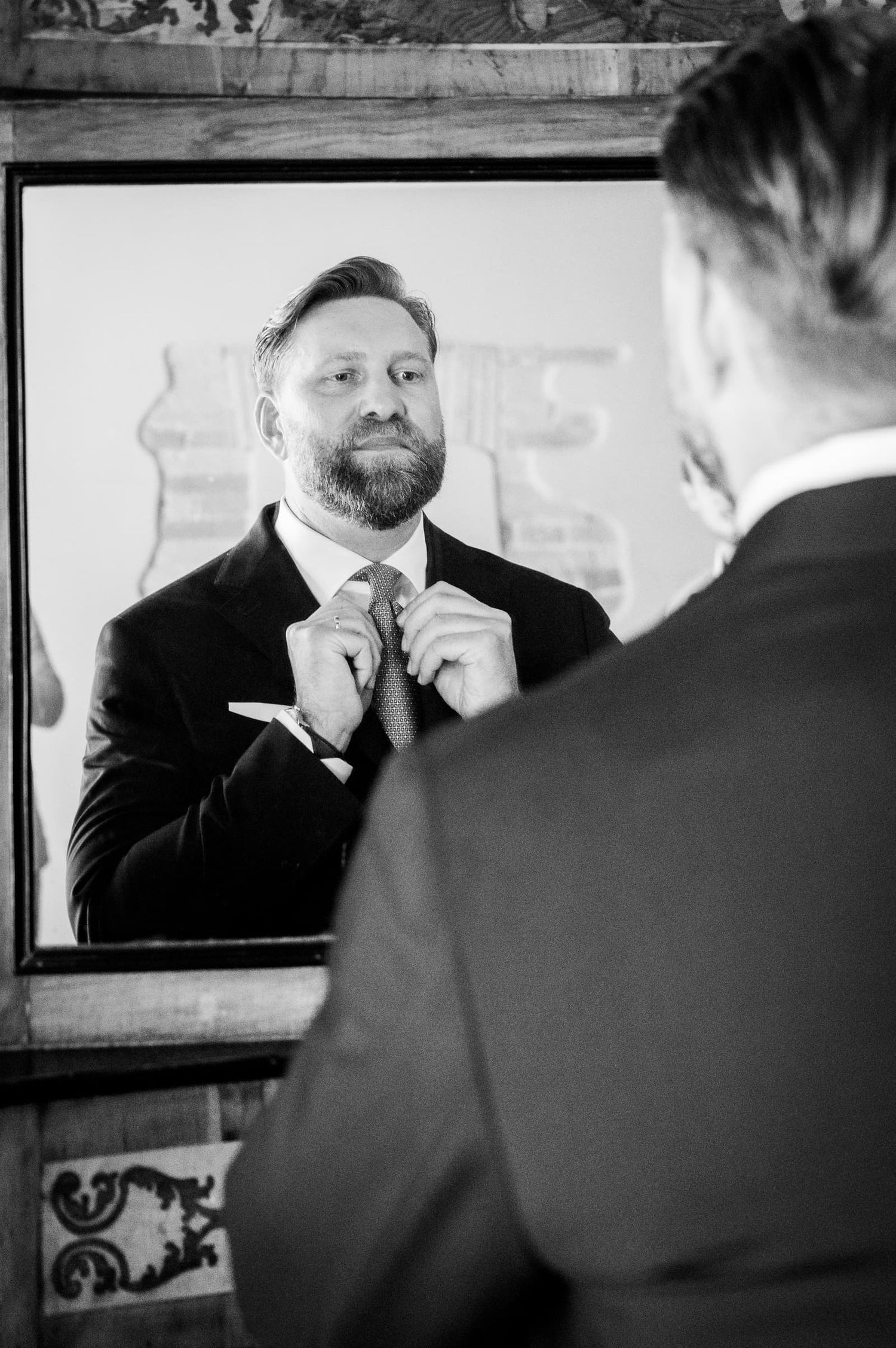 The groom smiling in the mirror in black and white, wedding at Borgo San Faustino, Umbria