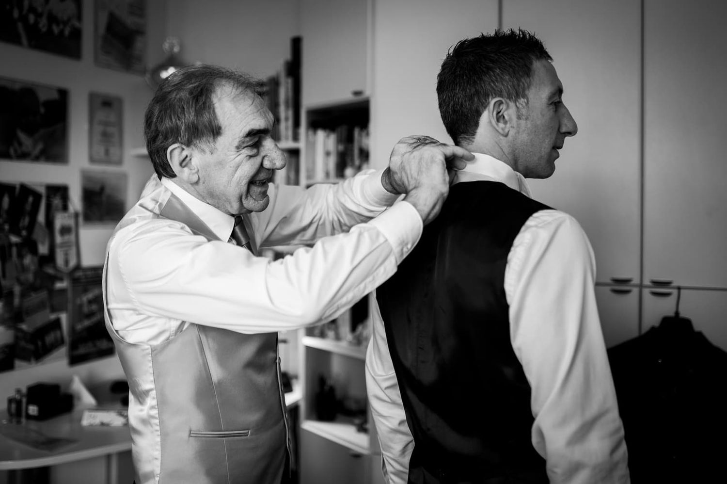 Un familiare aiuta lo sposo a indossare il gilet durante i preparativi, matrimonio invernale in Toscana
