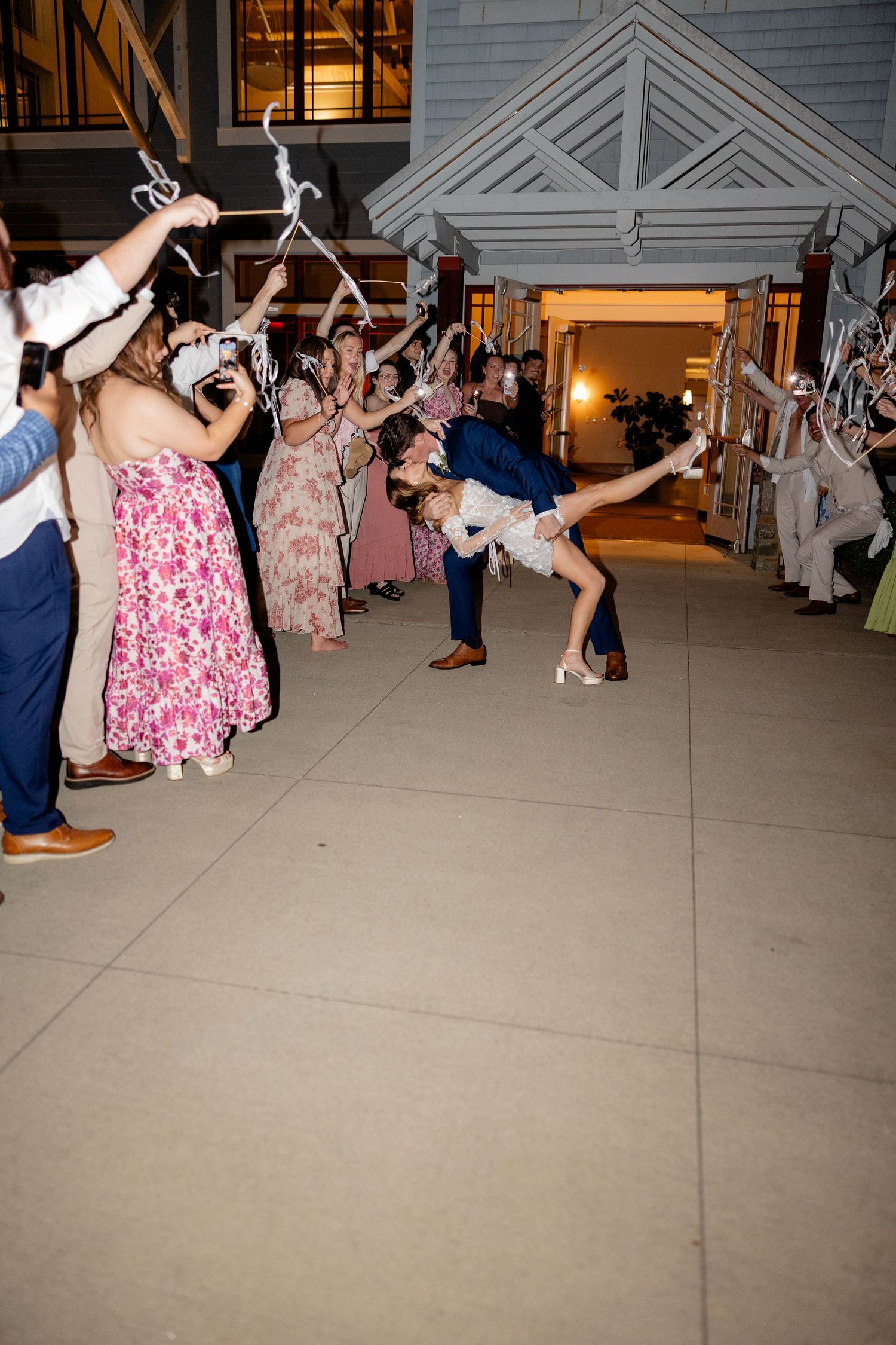 Wedding reception guests dancing and celebrating on an outdoor patio at night.
