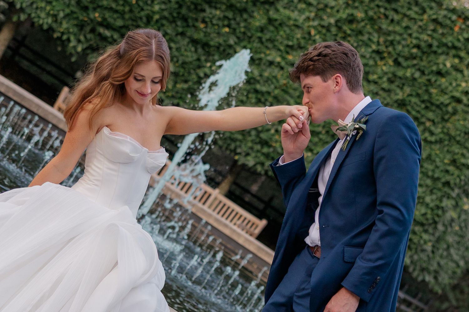Couple sharing romantic moments by an ivy-covered wall and fountain.