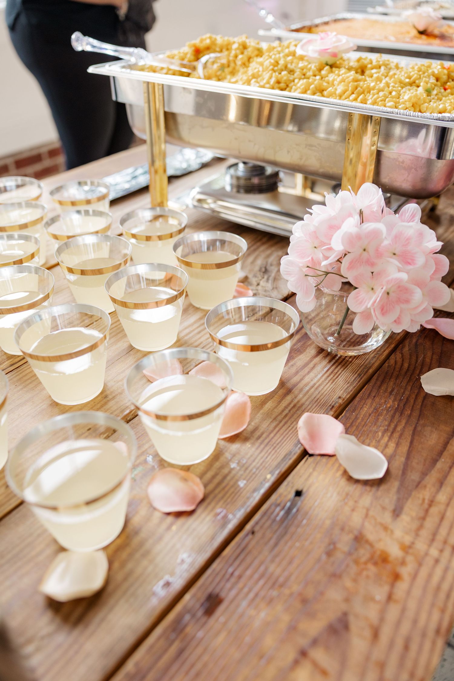 Elegant wedding buffet setup with chafing dish and champagne glasses decorated with pink flowers.