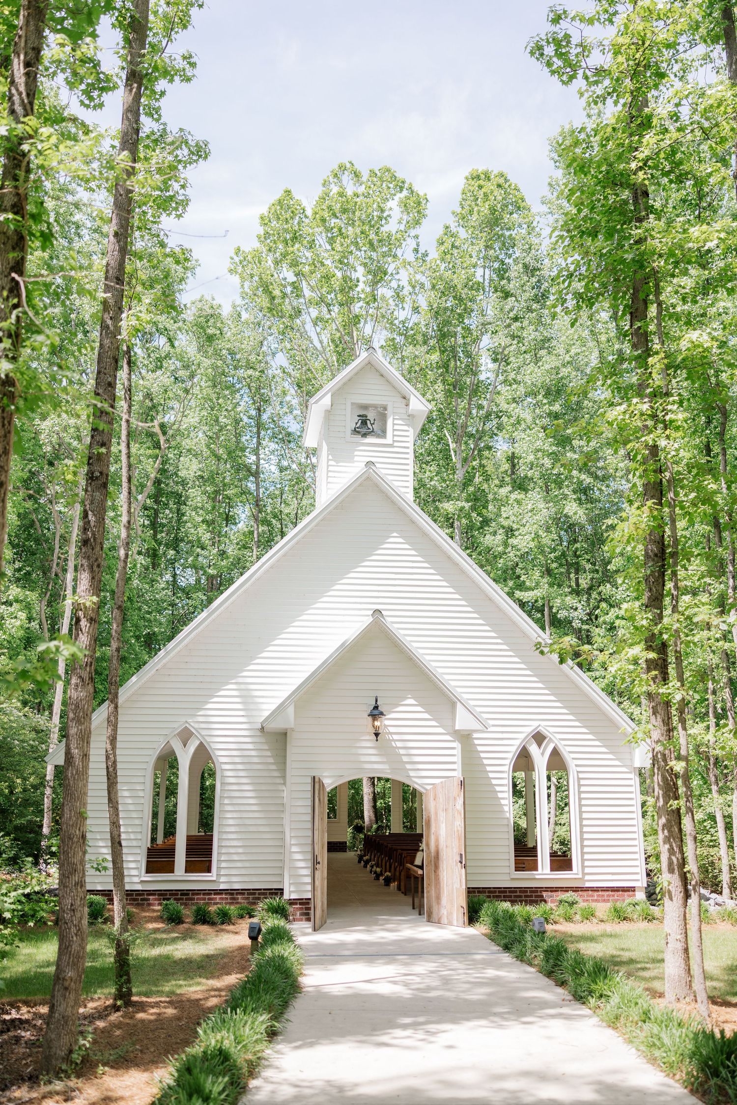 Beautiful white chapel nestled among tall trees in a serene woodland setting.