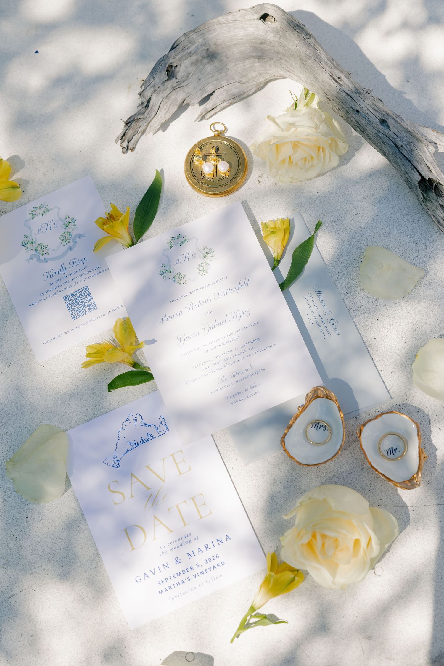 Wedding stationery flat lay with save the date, invitations, yellow flowers, and oyster ring dishes.