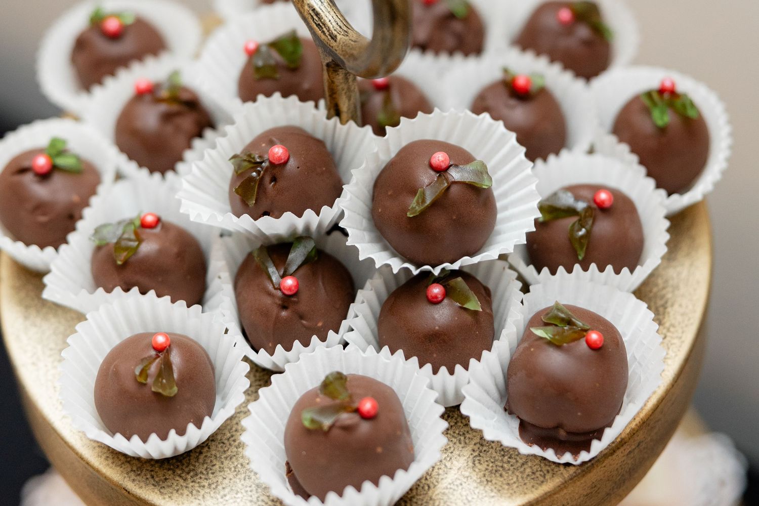Chocolate truffles decorated with tiny red hearts arranged on a gold serving platter.