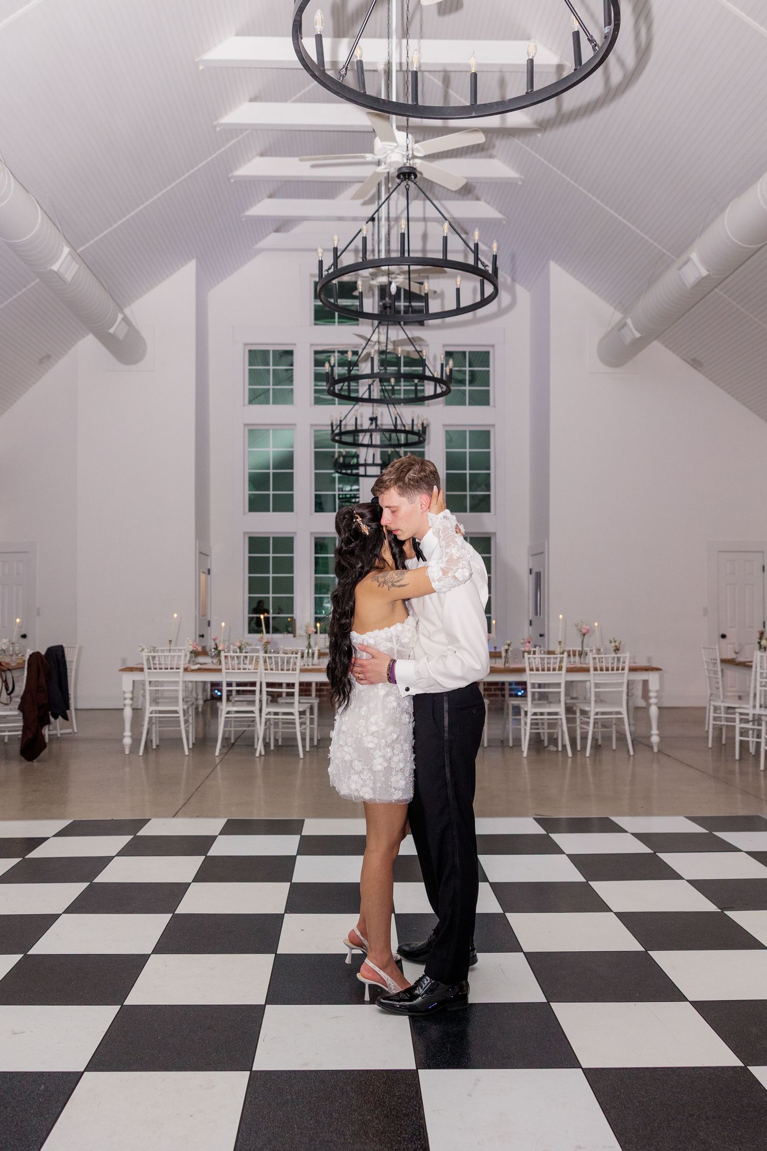 Wedding reception venue featuring a black and white checkered floor and elegant chandelier.