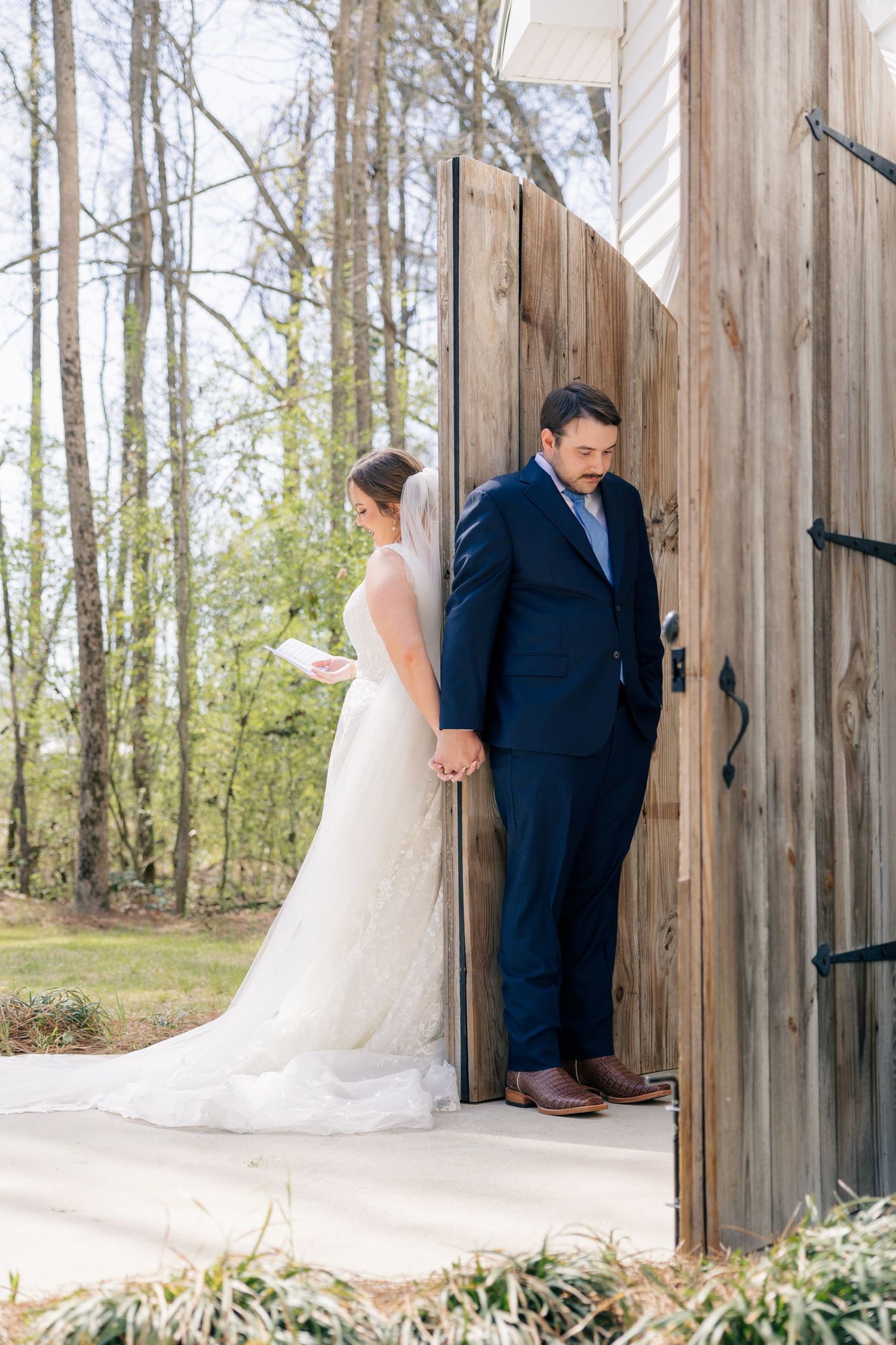 Wedding couple poses in front of rustic wooden barn doors creating romantic portrait shots.