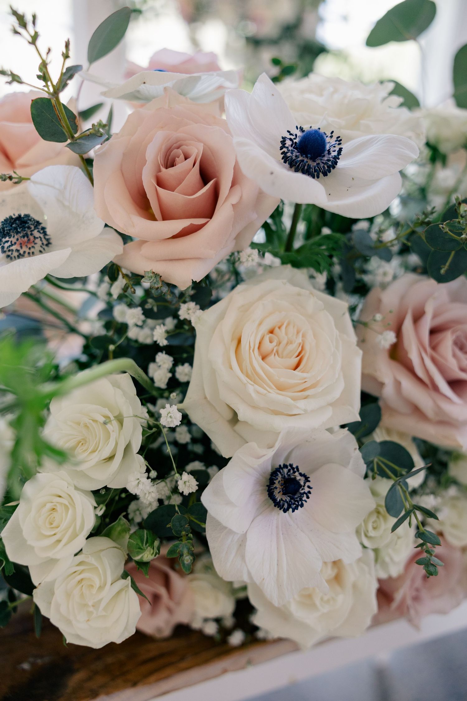 Wedding bouquet featuring pink and white roses with anemones and baby's breath flowers.