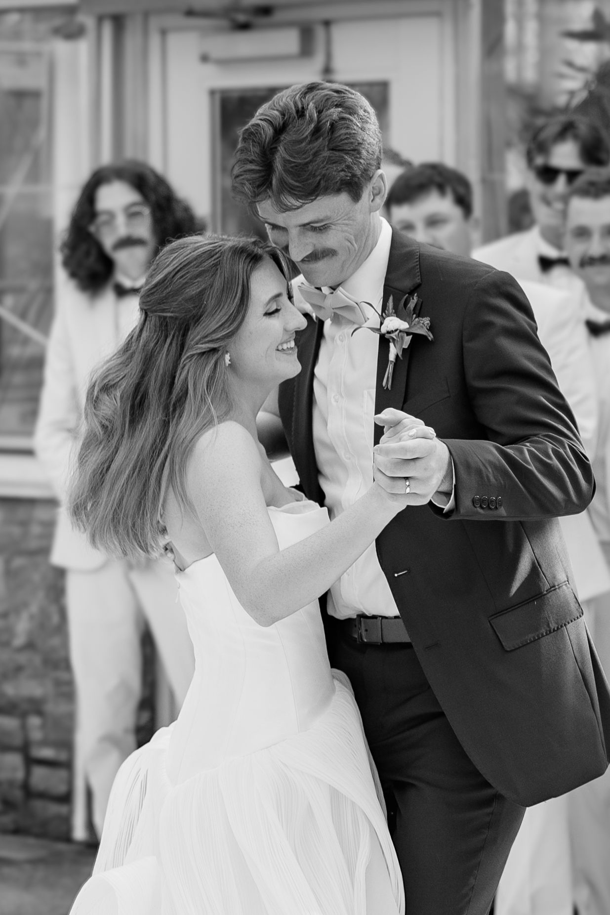 Black and white romantic dance sequence showing a couple in formal wedding attire.