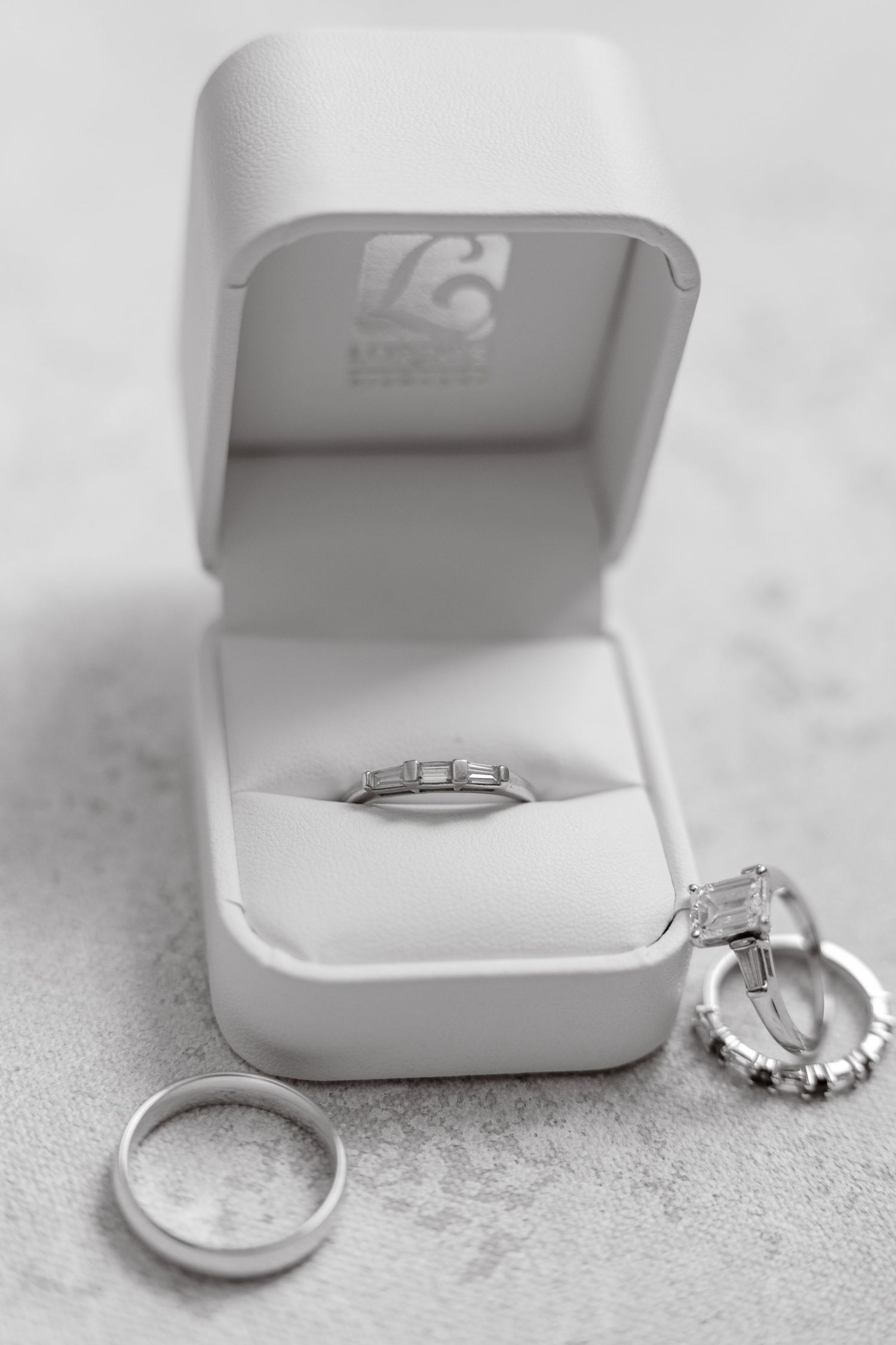 Black and white photo of diamond wedding rings in white jewelry box.