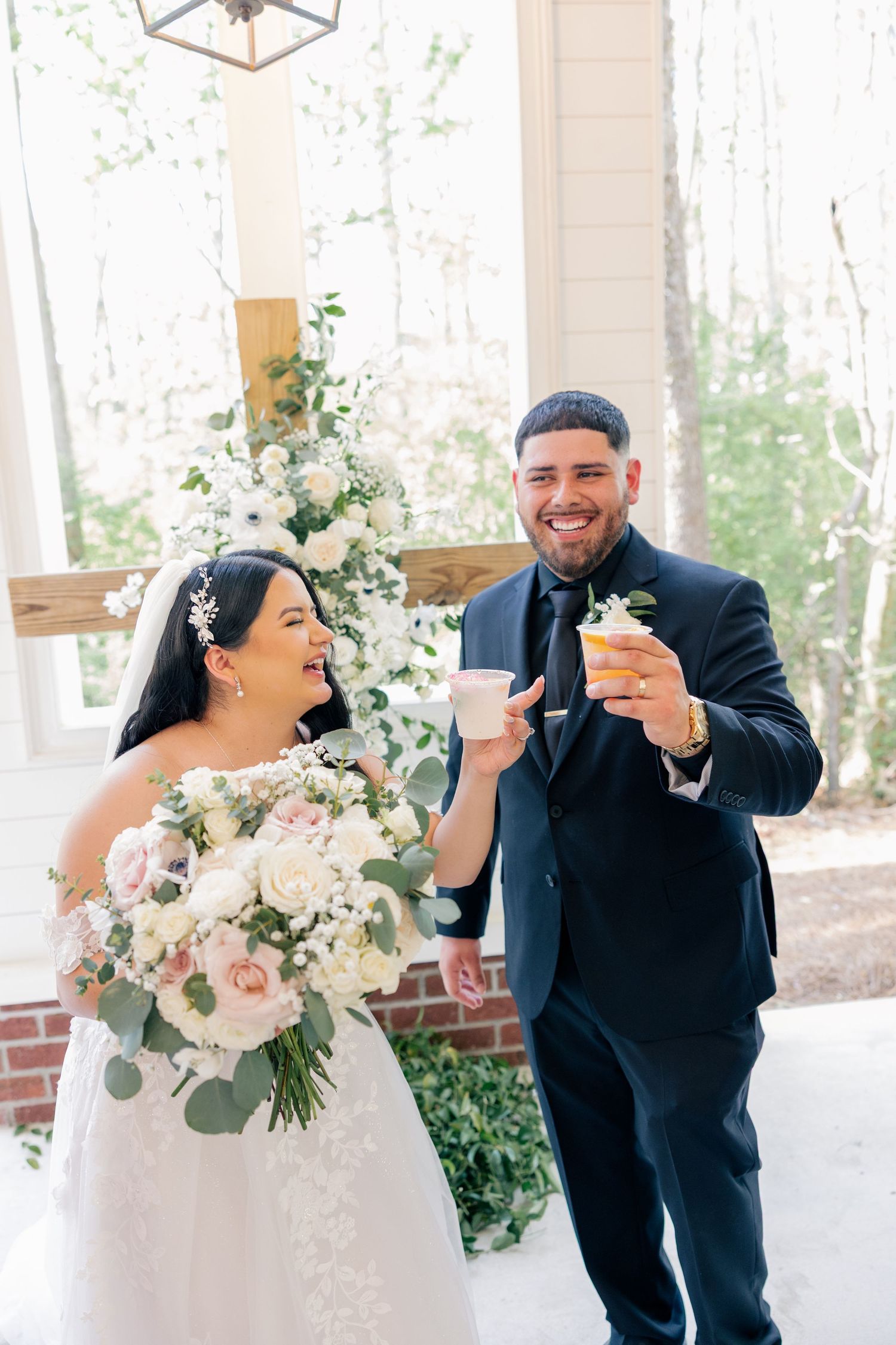 Joyful couple shares laughs during wedding portraits under covered porch.