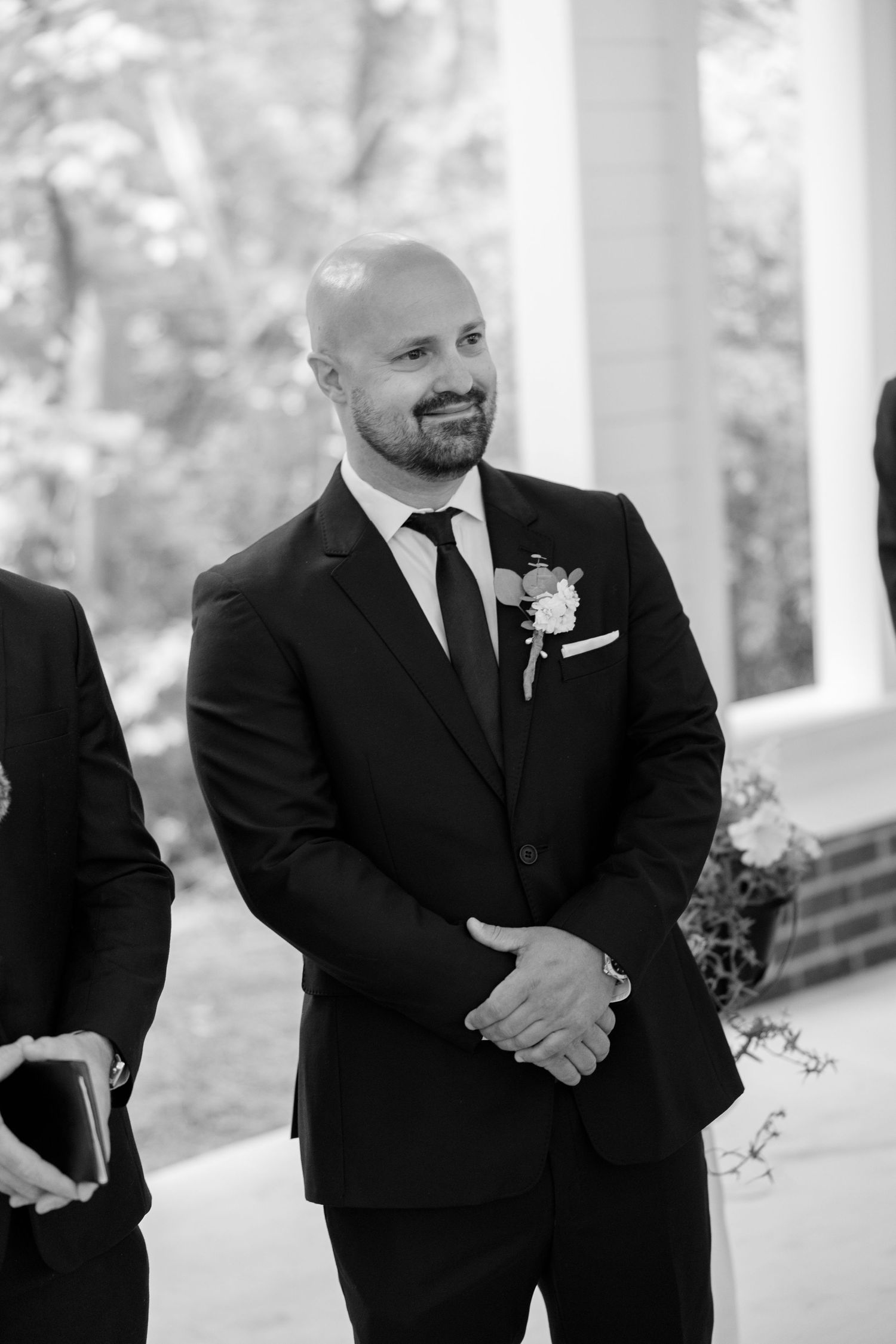 Groomsmen in black suits and ties standing together before wedding ceremony.