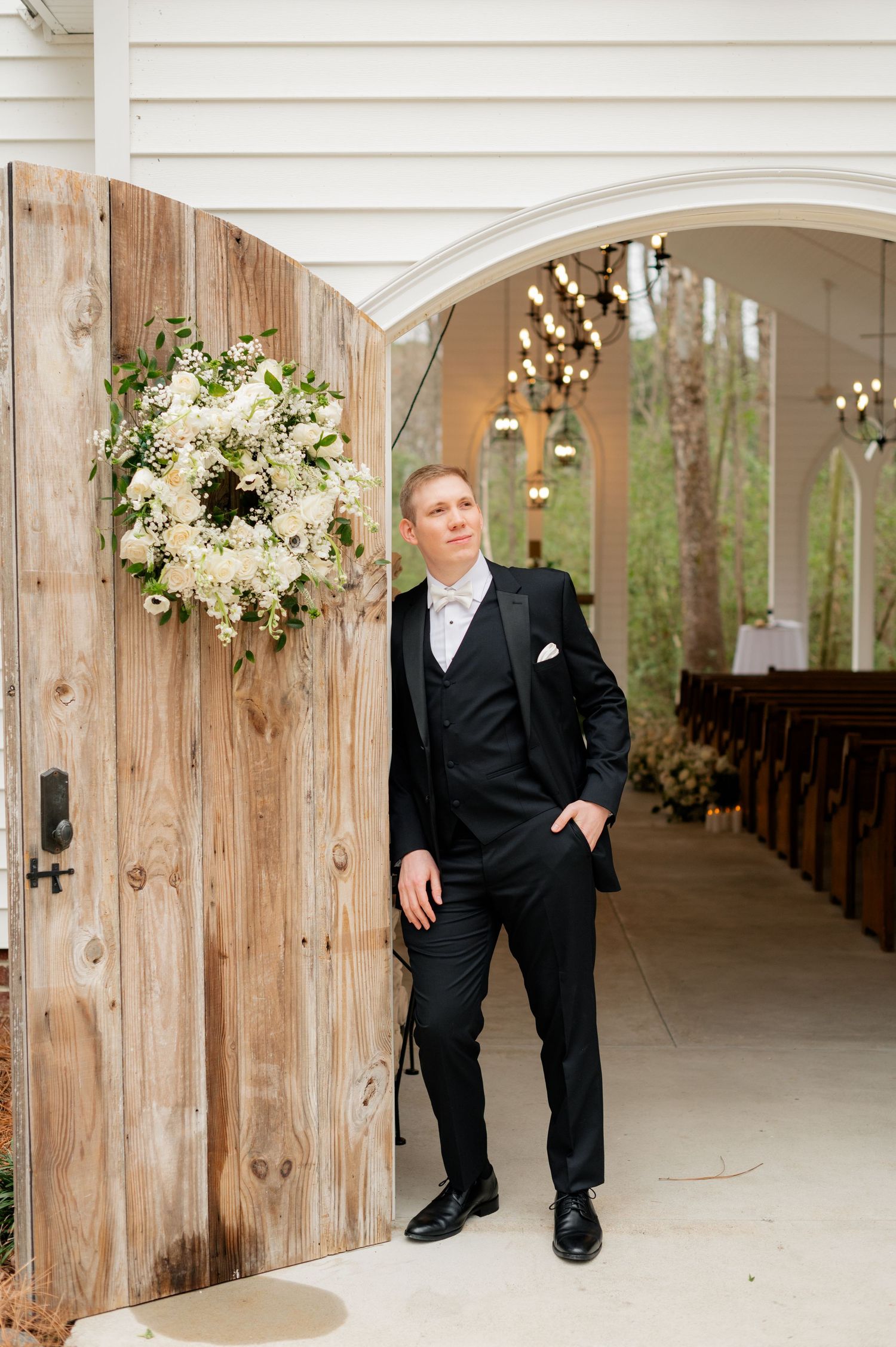 Wedding venue interior with rustic wooden details and floral arrangements hanging from arches.