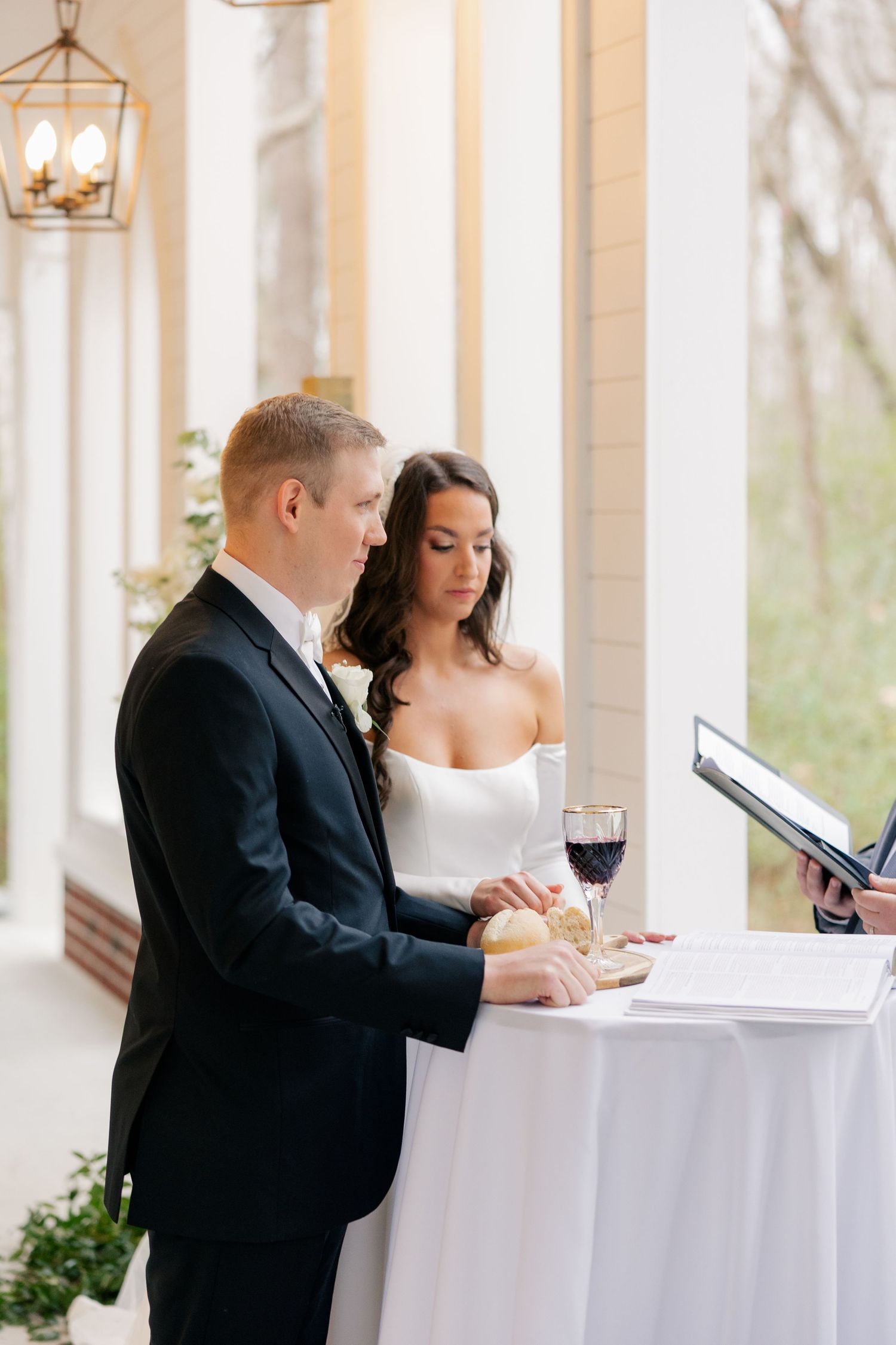 Couple seated at elegant white-clothed table during wedding reception.