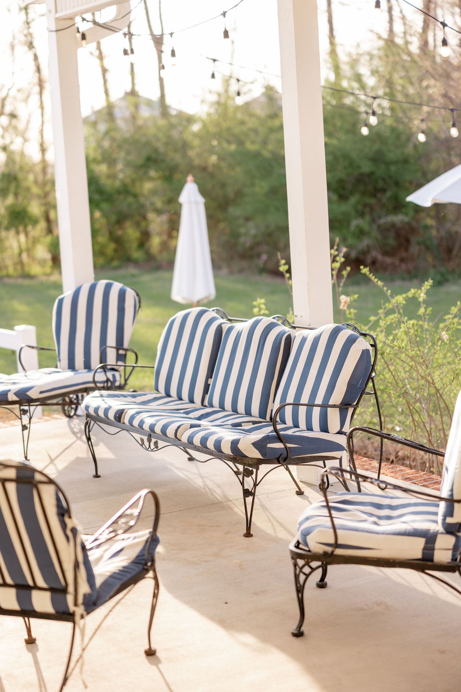 Outdoor seating area with blue and white striped cushioned benches under a covered porch.