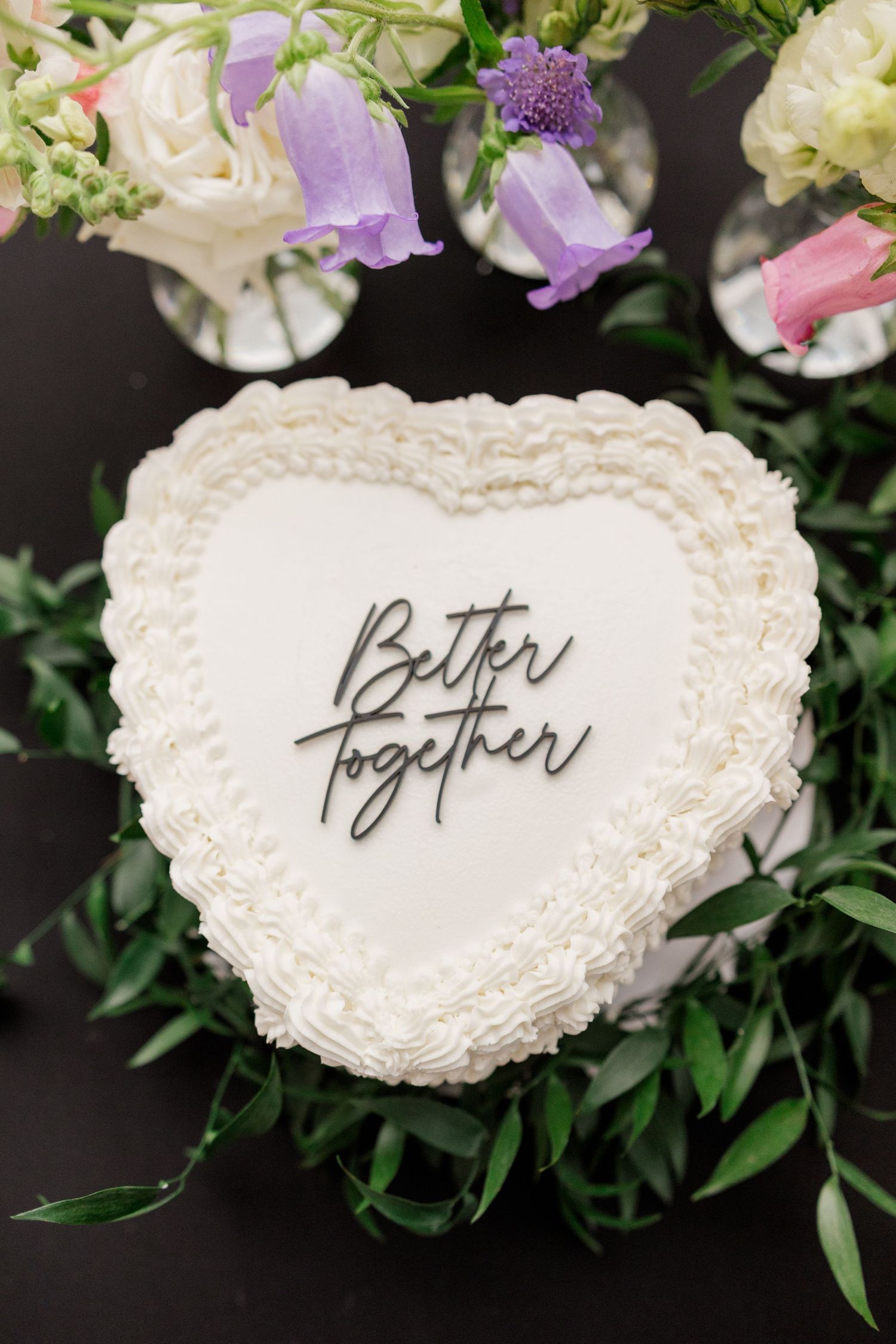 White heart-shaped wedding cake decorations with calligraphy text surrounded by delicate flowers.