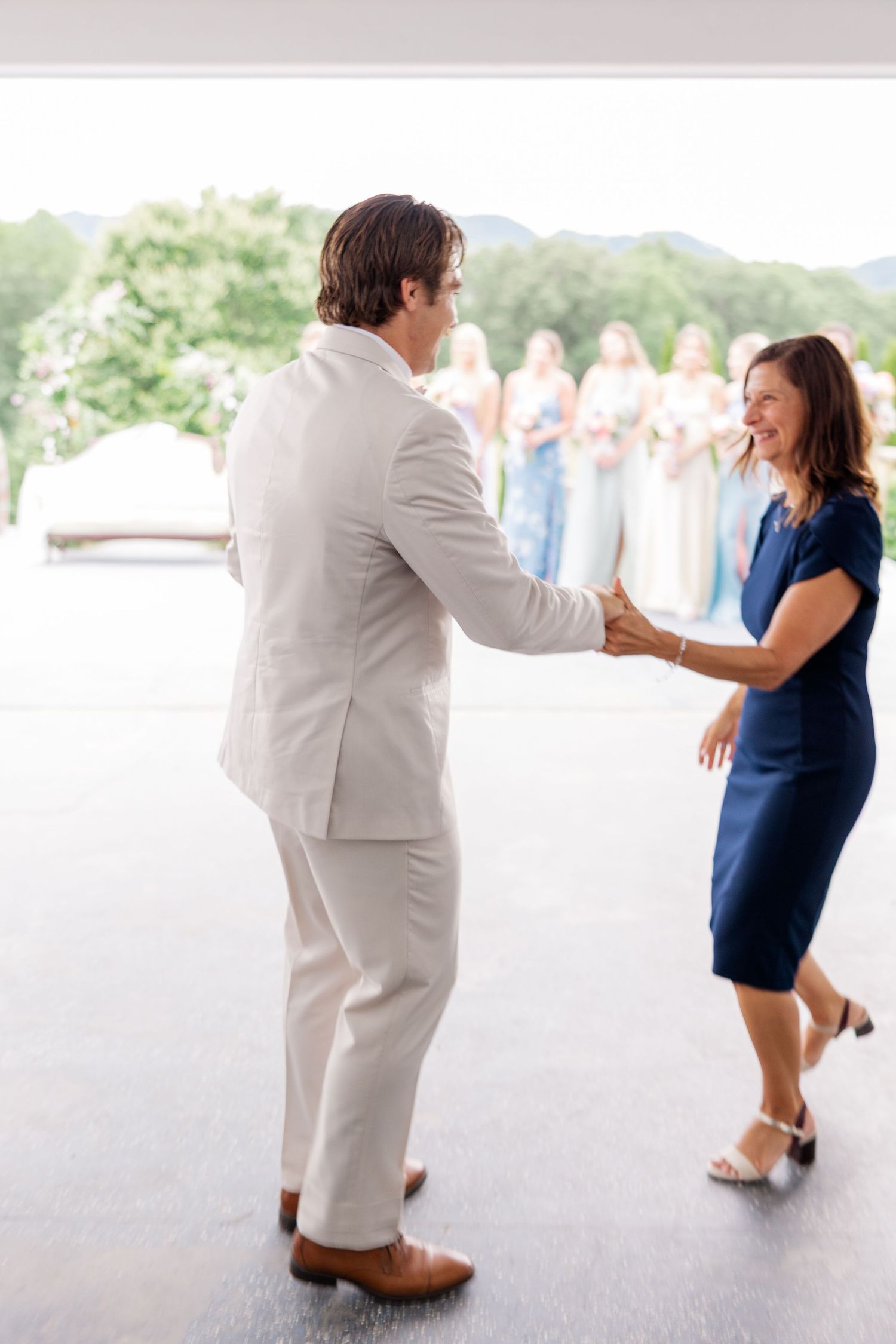 A couple dances together on a white patio during their wedding celebration.