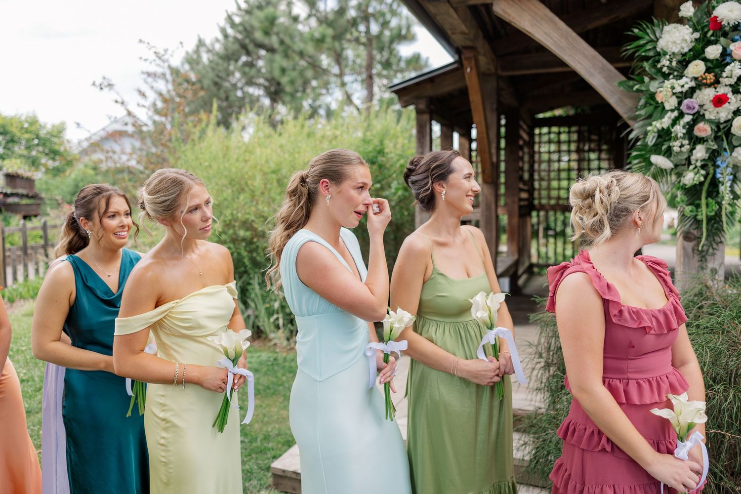 Wedding party in colorful dresses walking along a garden path.