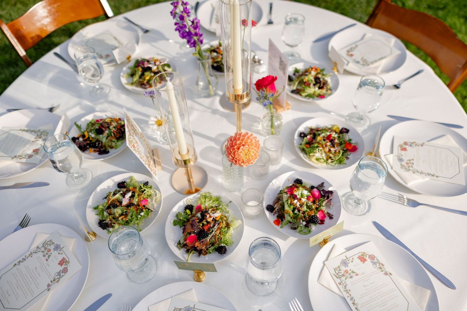 Elegant wedding reception tables set with fresh salads and floral centerpieces.