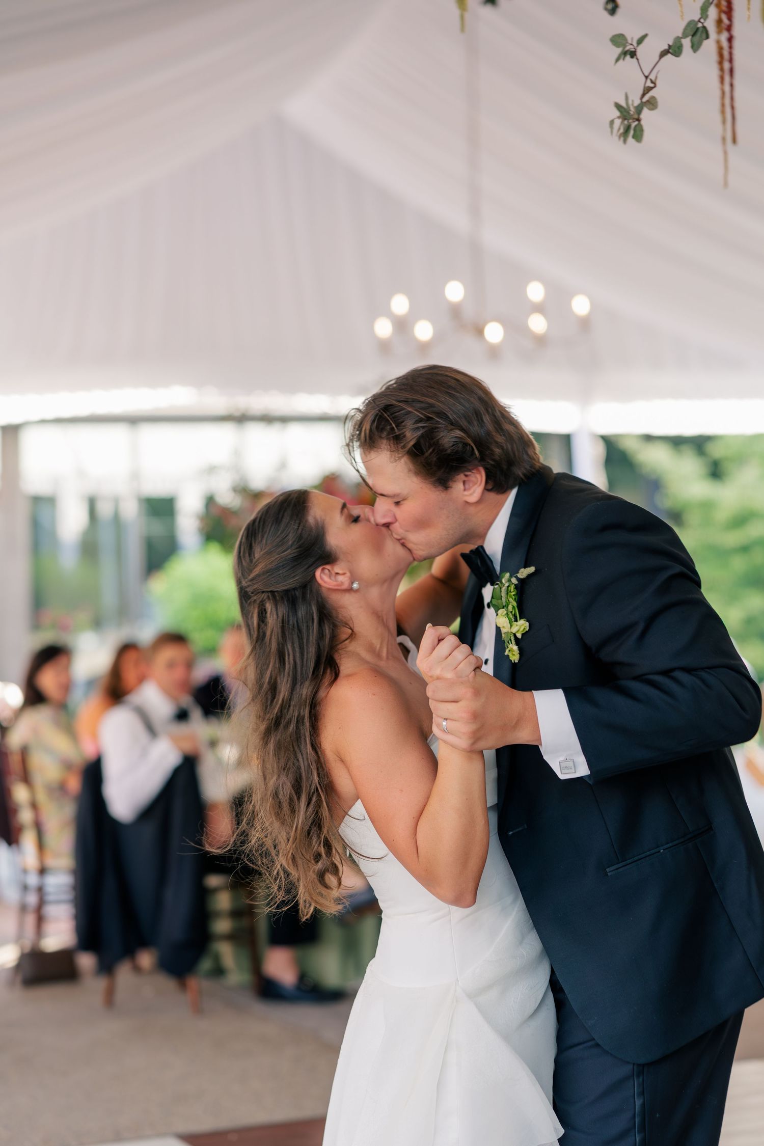 Bride and groom share a passionate kiss during their first dance at an elegant tented wedding reception.