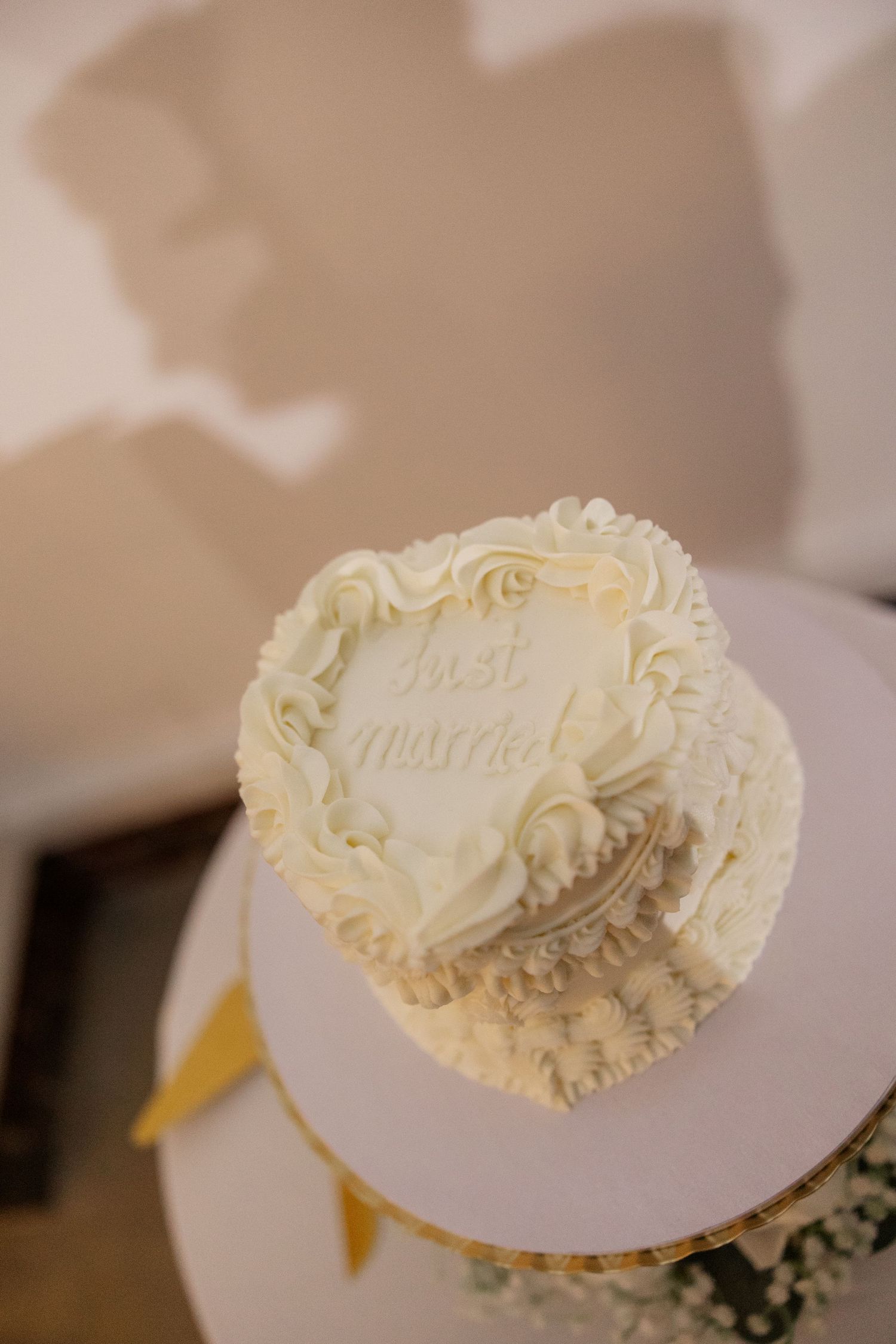 Close-up of an ornate white wedding cake detail with delicate piping design.
