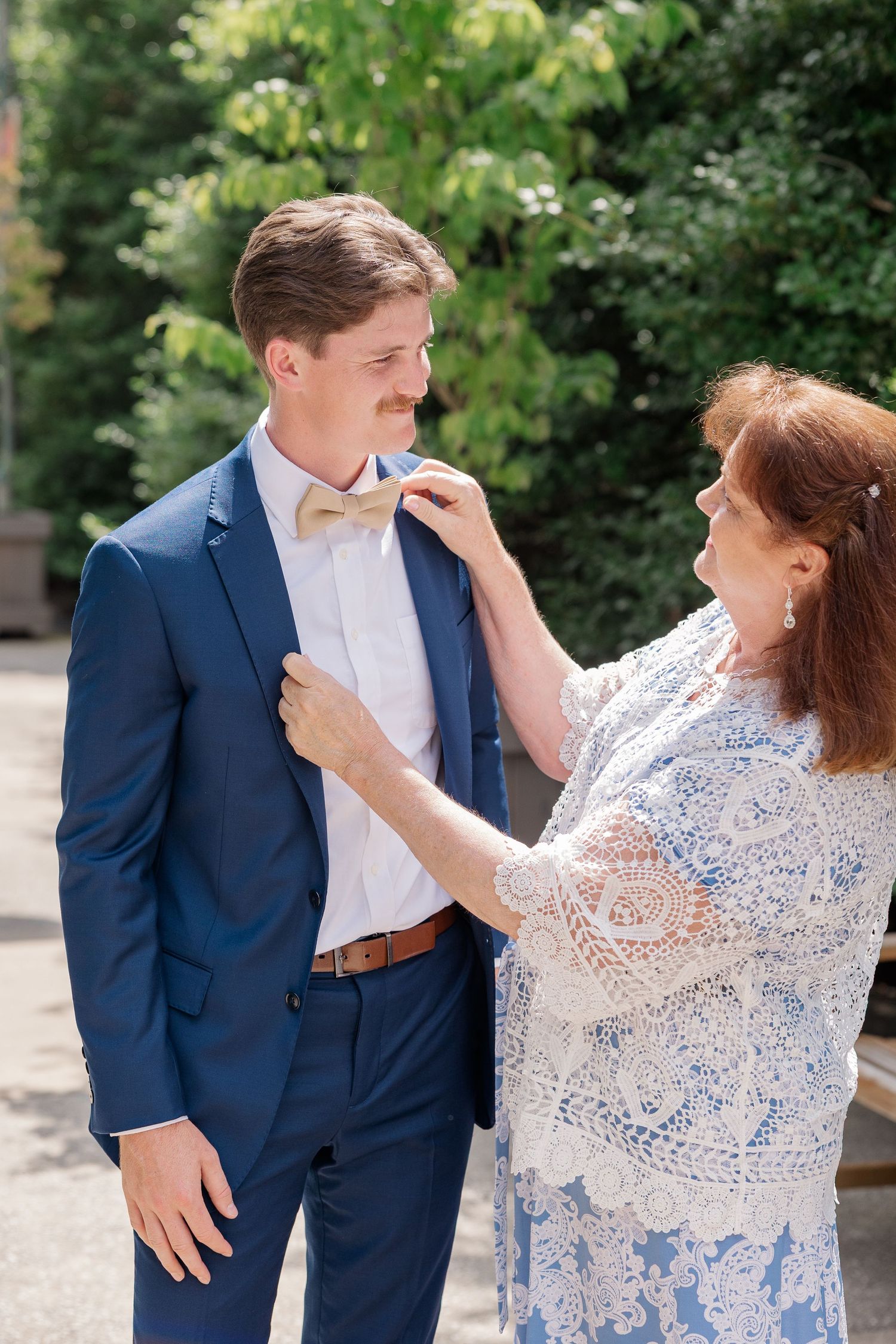 Playful outdoor wedding photoshoot showing couple in blue suit and lace dress.