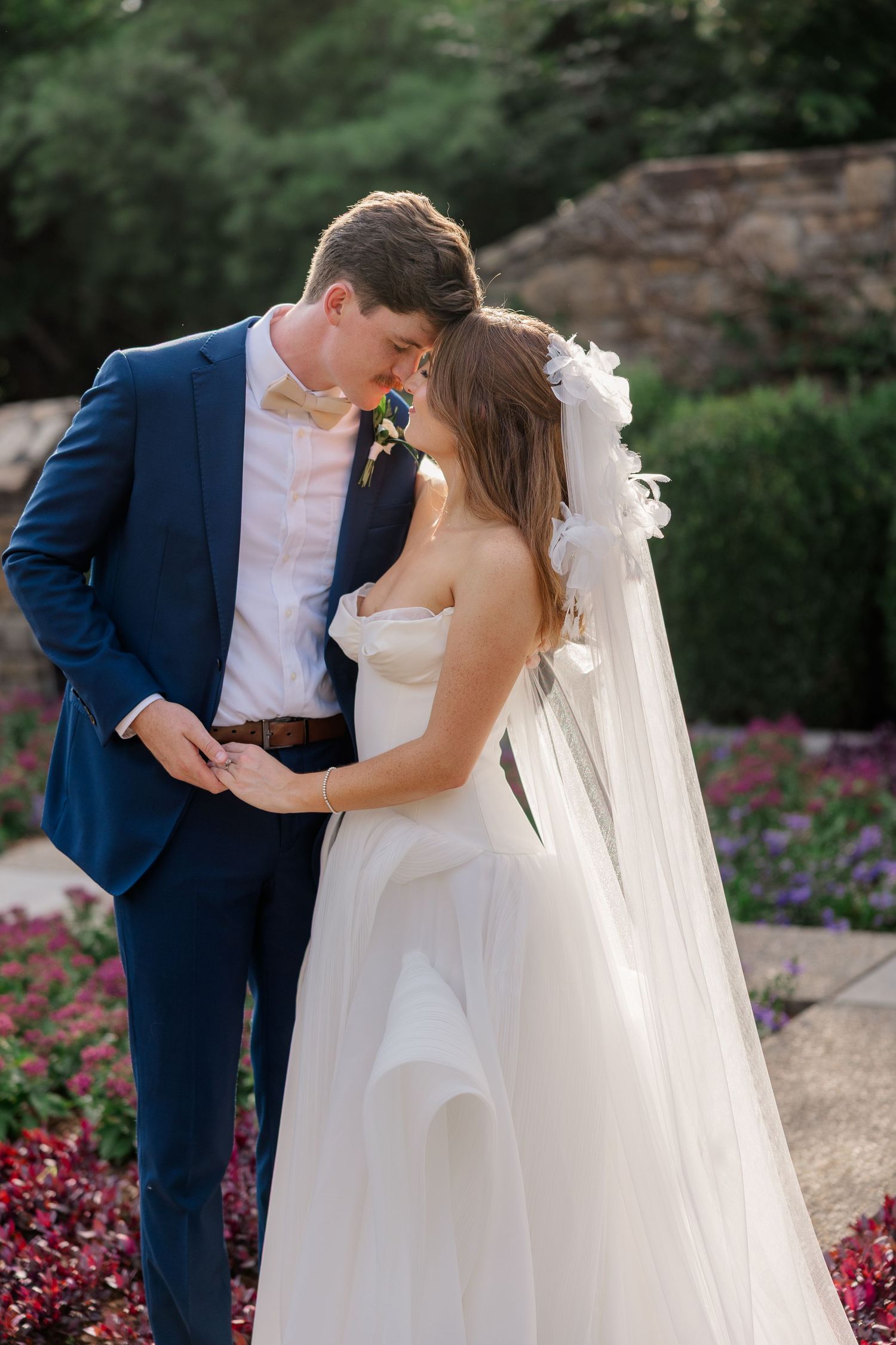 Romantic wedding couple shares intimate moments in a garden setting with colorful flowers.