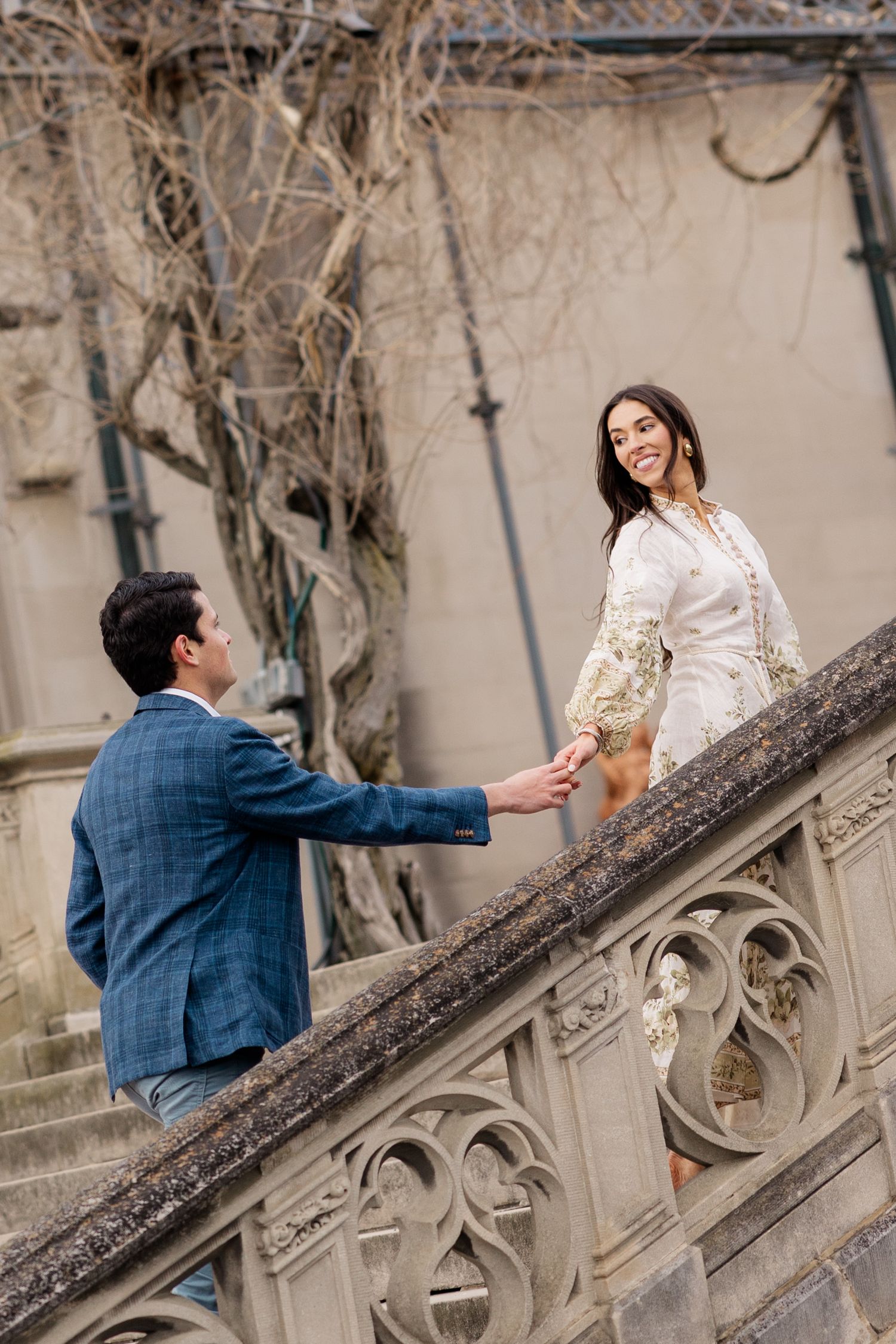 A romantic moment on ornate stone steps as a couple shares a tender interaction at a historic building.