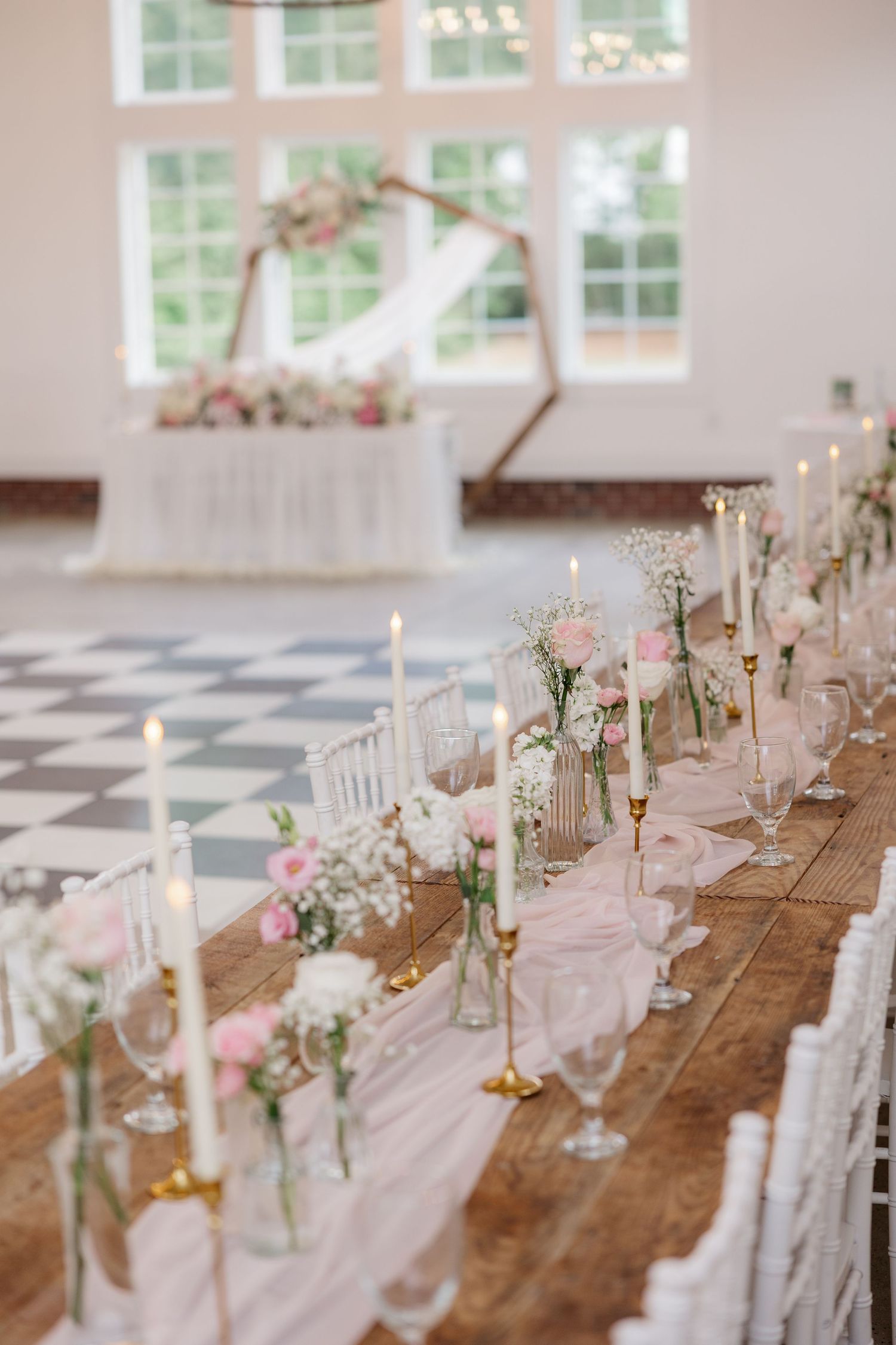 Elegant table setting with white chairs and pink accents for wedding reception.
