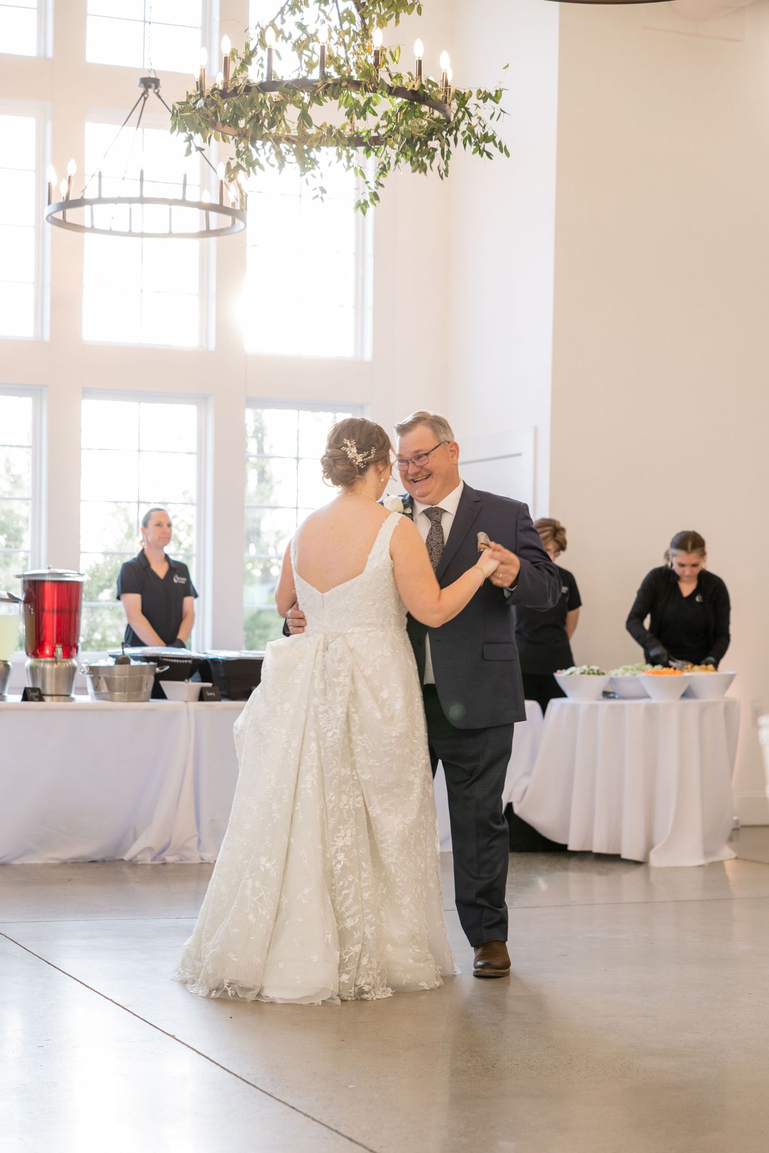Reception venue with white decor and hanging greenery in bright indoor space.