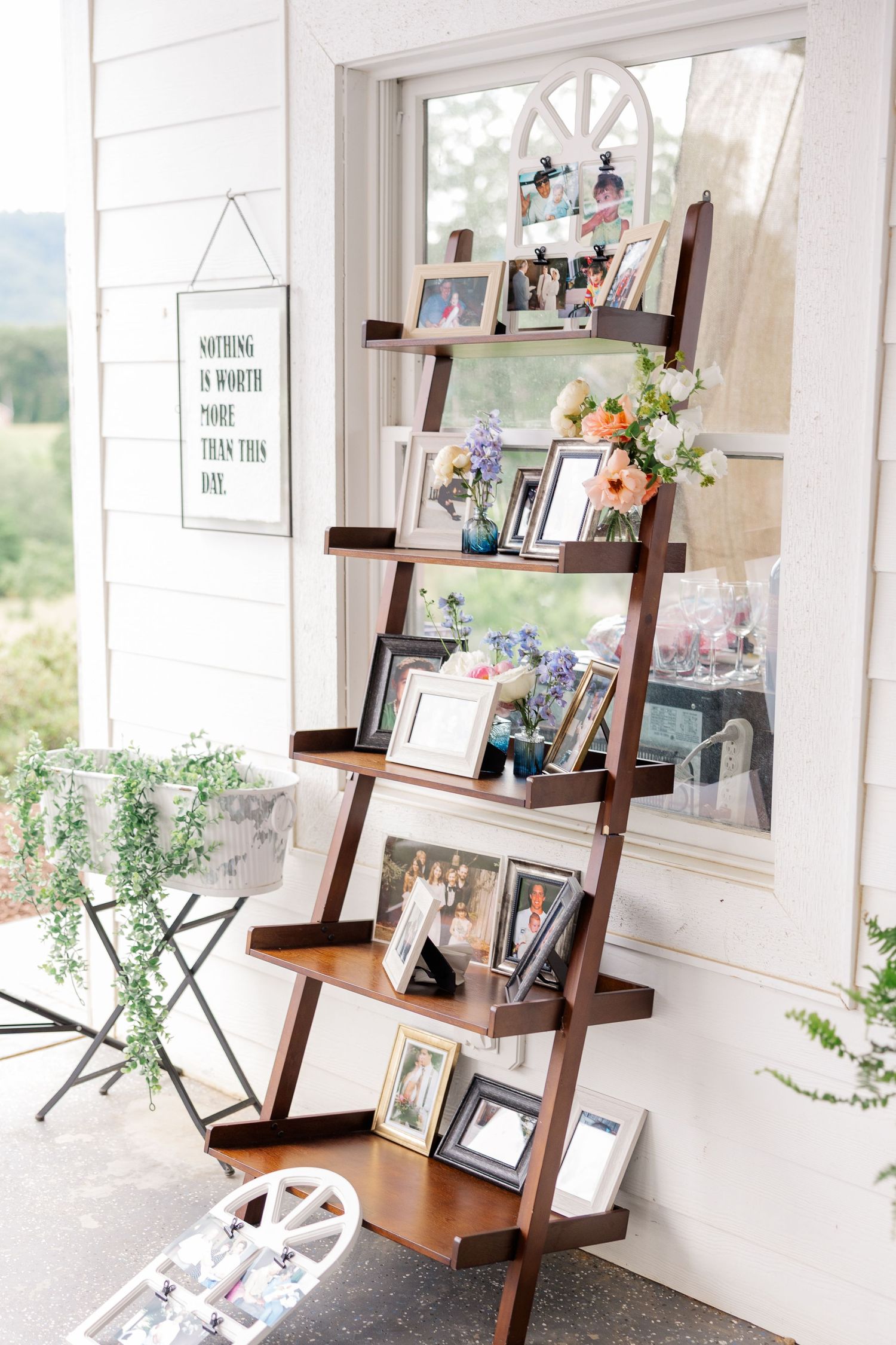 White room with ladder shelf displaying photos and decor near bright windows.