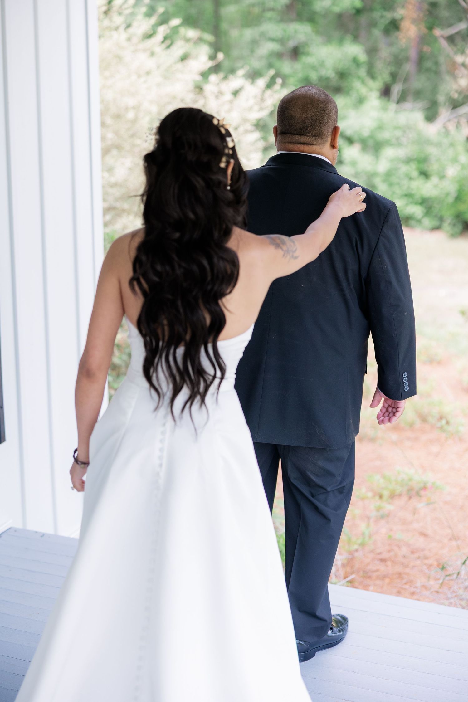 Wedding party walking together outdoors in formal attire against a forested backdrop.
