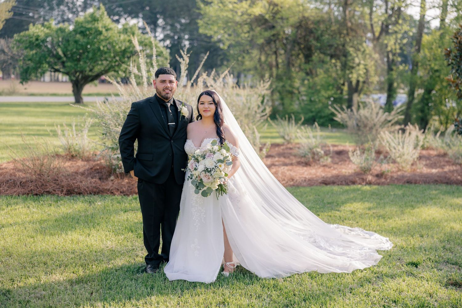 Wedding couple poses for romantic portraits in a sun-dappled outdoor setting.