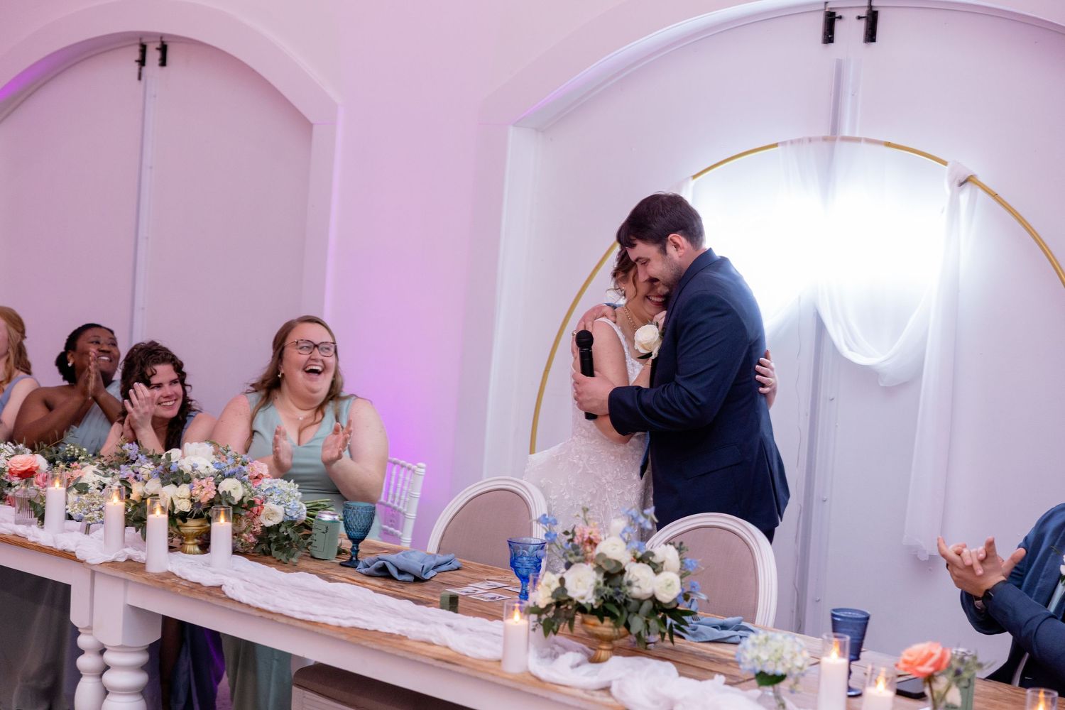 Wedding reception venue with purple lighting and guests seated at decorated tables.