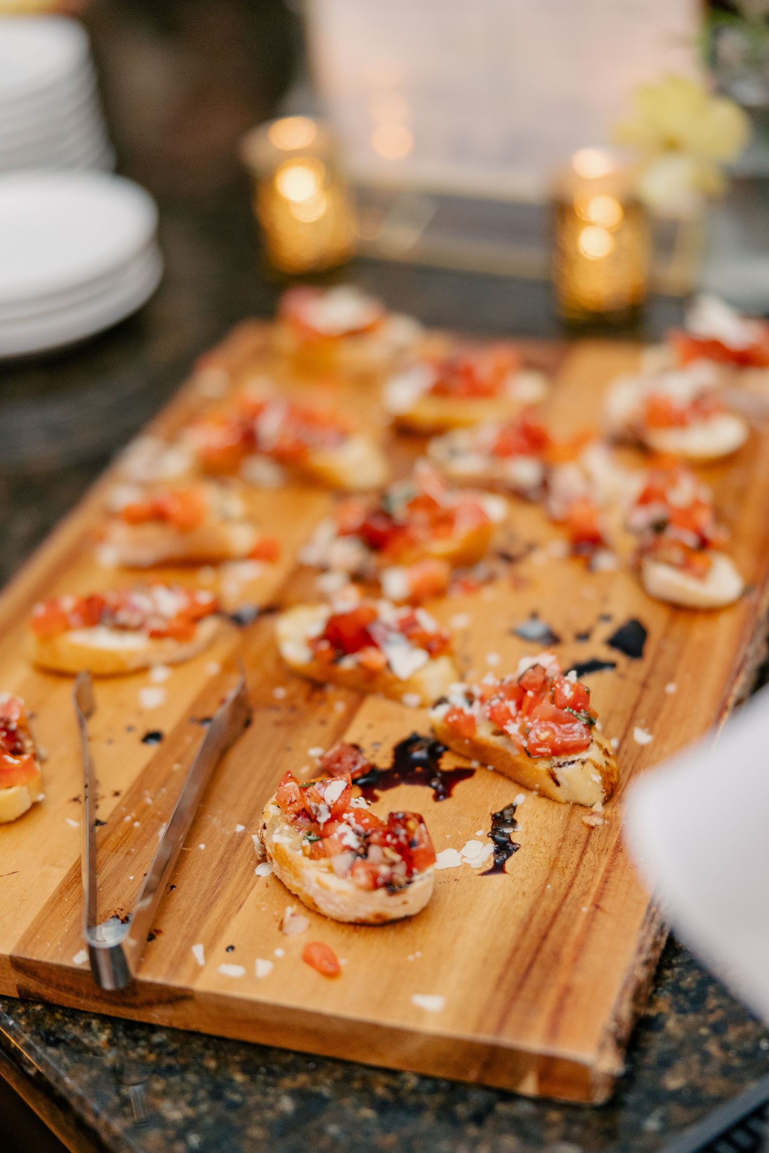 Bruschetta appetizers topped with tomatoes and balsamic glaze arranged on wooden serving board at wedding.
